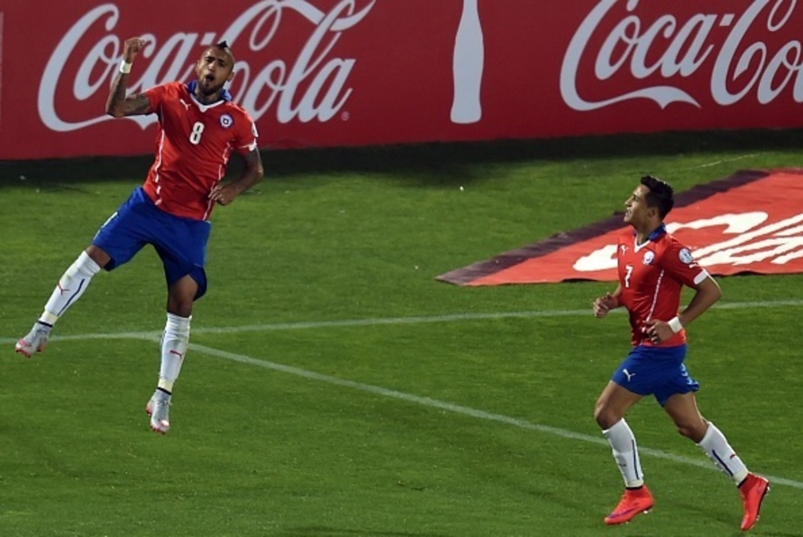 Chile's midfielder Arturo Vidal (L) celebrates next to Chile's forward Alexis Sanchez after scoring a penalty against Ecuador, during the Copa America inauguration football match, on June 11, 2015 at the Nacional stadium in Santiago.     AFP PHOTO / RODRI