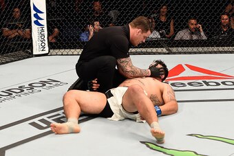 BRISBANE, AUSTRALIA - MARCH 20:  Referee Marc Goddard tends to Frank Mir of the United States as he lies on the Octagon mat after being defeated by Mark Hunt of New Zealand by KO in their heavyweight bout during the UFC Fight Night event at the Brisbane E