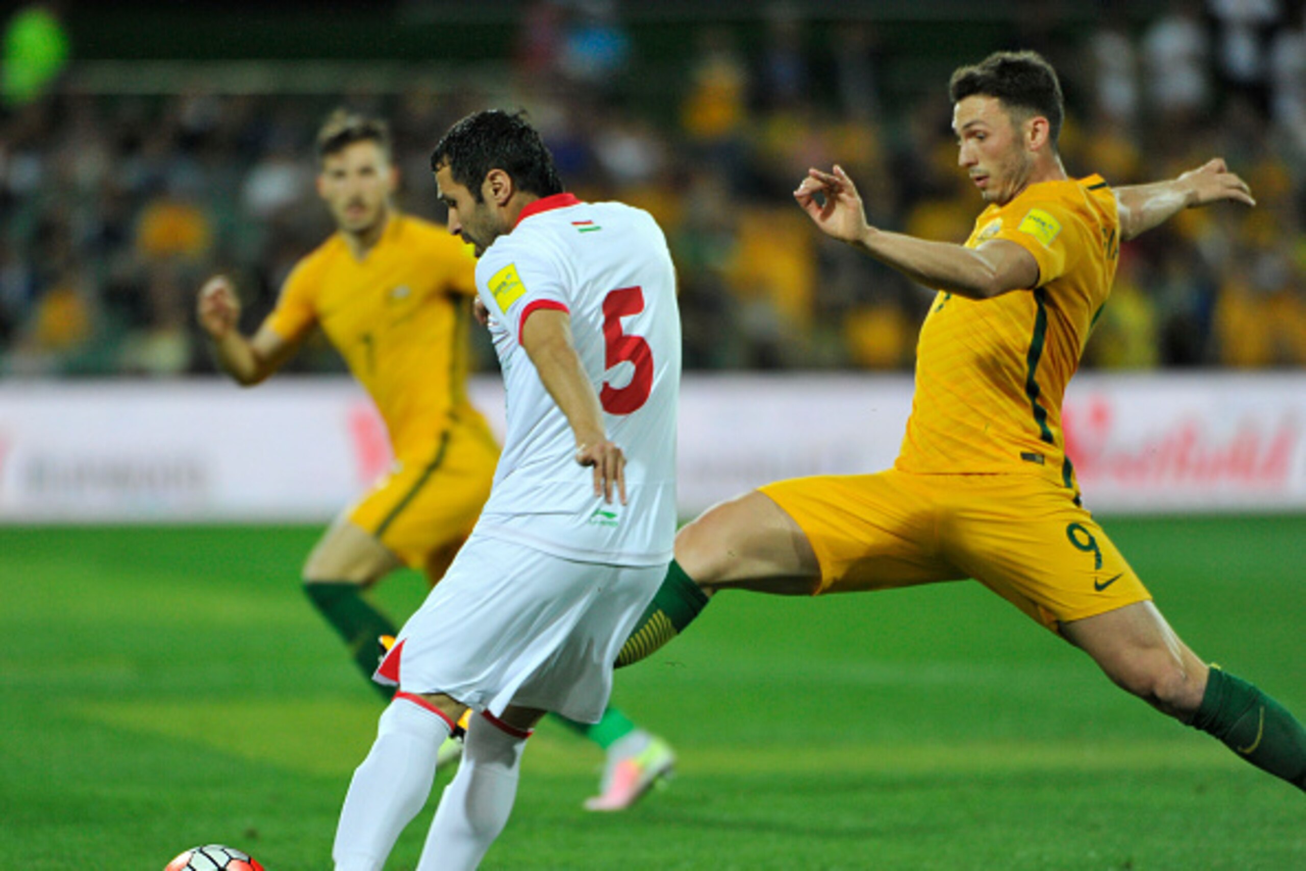 Dzhalilov Dzhakhongir from Tajikistan (L) is tackled by  Apostolos Giannou from Australia during the FIFA World Cup Asian qualifier football match between Australia and Tajikistan in Adelaide on March 24, 2016. / AFP / David Mariuz / IMAGE RESTRICTED TO E