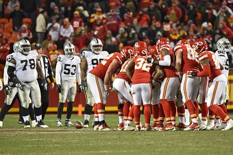 KANSAS CITY, MO - JANUARY 03:  The Kansas City Chiefs huddle as the Oakland Raiders defense looks on during the second half on January 3, 2016 at Arrowhead Stadium in Kansas City, Missouri.  (Photo by Peter G. Aiken/Getty Images)