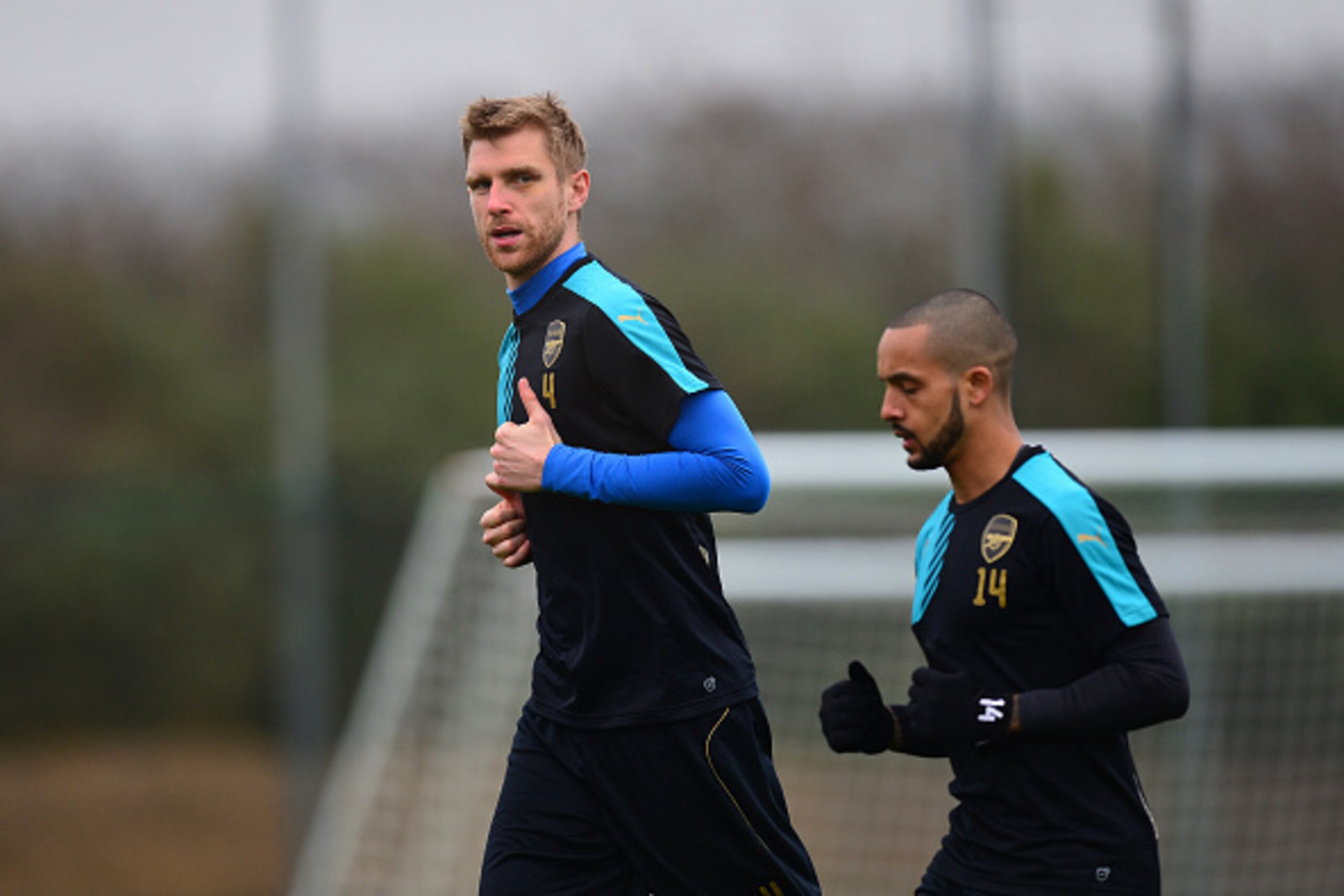 ST ALBANS, ENGLAND - MARCH 15:  Per Mertesacker runs with team-mate Theo Walcott of Arsenal during a training session ahead of the UEFA Champions League round of 16 second leg match between Barcelona and Arsenal at London Colney on March 15, 2016 in St Al