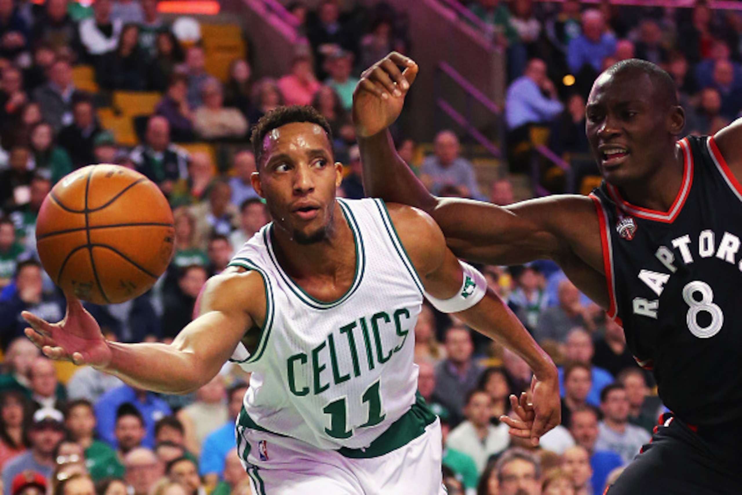 BOSTON, MA - MARCH 23:  Evan Turner #11 of the Boston Celtics saves a rebound from going out of bounds with pressure from Bismack Biyombo #8 of the Toronto Raptors during the first quarter at TD Garden on March 23, 2016 in Boston, Massachusetts.  (Photo b
