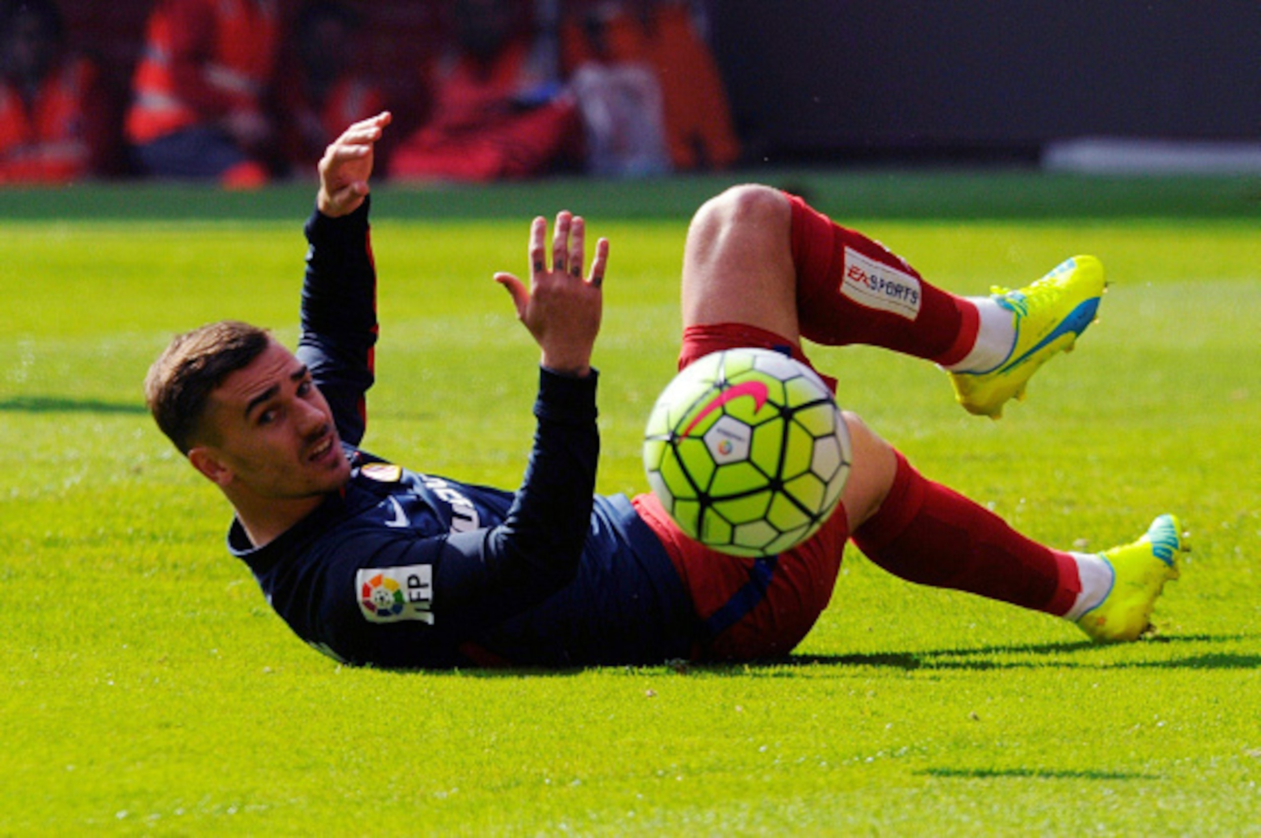 Atletico Madrid's French forward Antoine Griezmann looks at the ball as he lies on the ground during the Spanish league football match Real Sporting de Gijon vs Club Atletico de Madrid at El Molinon stadium in Gijon on March 19, 2016. Sporting won the mat