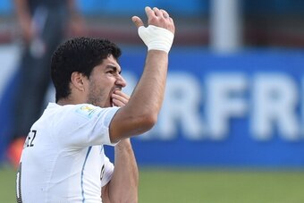 Uruguay forward Luis Suarez puts his hand to his mouth after clashing with Italy's defender Giorgio Chiellini during a Group D football match between Italy and Uruguay at the Dunas Arena in Natal during the 2014 FIFA World Cup on June 24, 2014. Uruguay wo