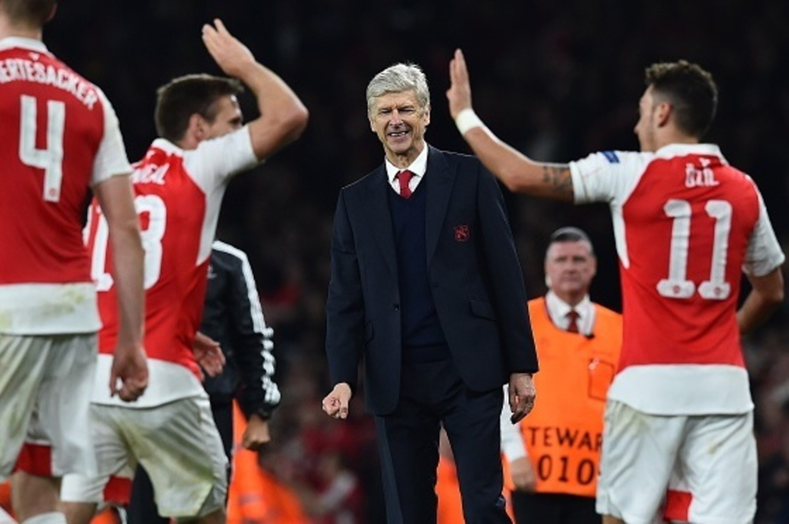Arsenal's French manager Arsene Wenger (C) watches as Arsenal's German midfielder Mesut Ozil (R) celebrates scoring his team's second goal with teamamte Arsenal's Spanish defender Nacho Monreal during the UEFA Champions League football match between Arsen
