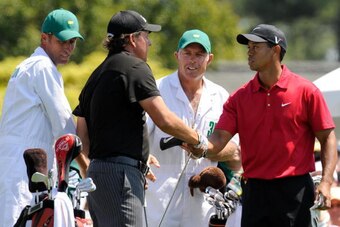 US golfers Phil Mickelson (2nd L) and Tiger Woods (R) shake hands before teeing off on the first hole as their caddies Jim MacKay (L) and Steve Williams look on during the final round of the US Masters at the Augusta National Golf Club on April 12, 2009. 
