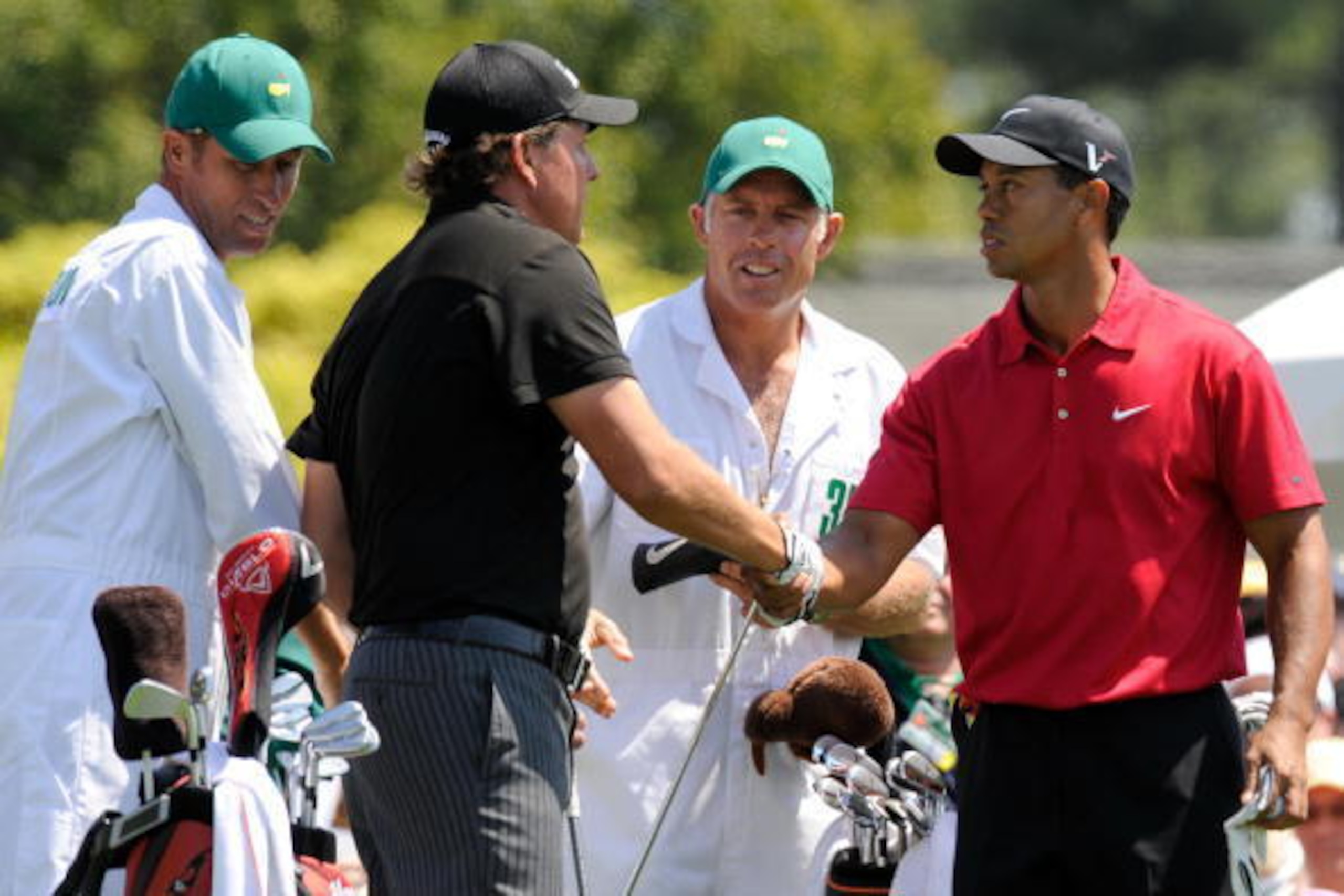 US golfers Phil Mickelson (2nd L) and Tiger Woods (R) shake hands before teeing off on the first hole as their caddies Jim MacKay (L) and Steve Williams look on during the final round of the US Masters at the Augusta National Golf Club on April 12, 2009. 