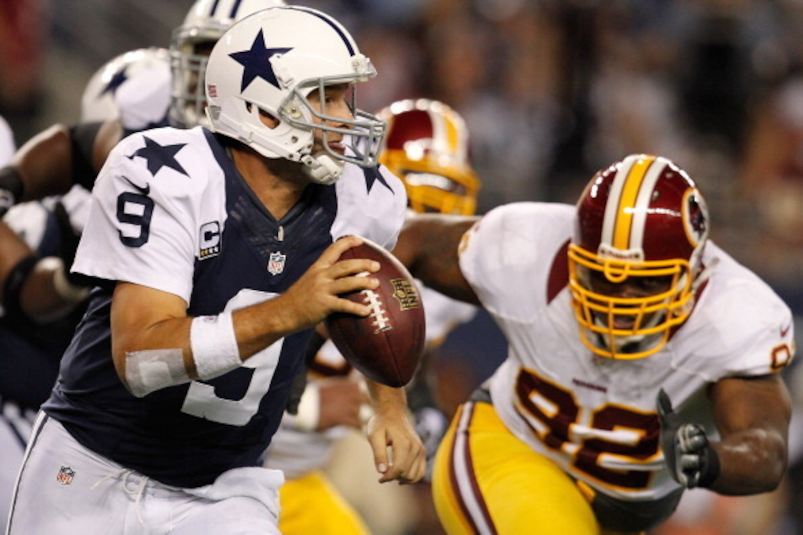 ARLINGTON, TX - NOVEMBER 22:  Tony Romo #9 of the Dallas Cowboys looks for an open receiver under pressure from Chris Baker #92 of the Washington Redskins on Thanksgiving Day at Cowboys Stadium on November 22, 2012 in Arlington, Texas. The Washington Reds