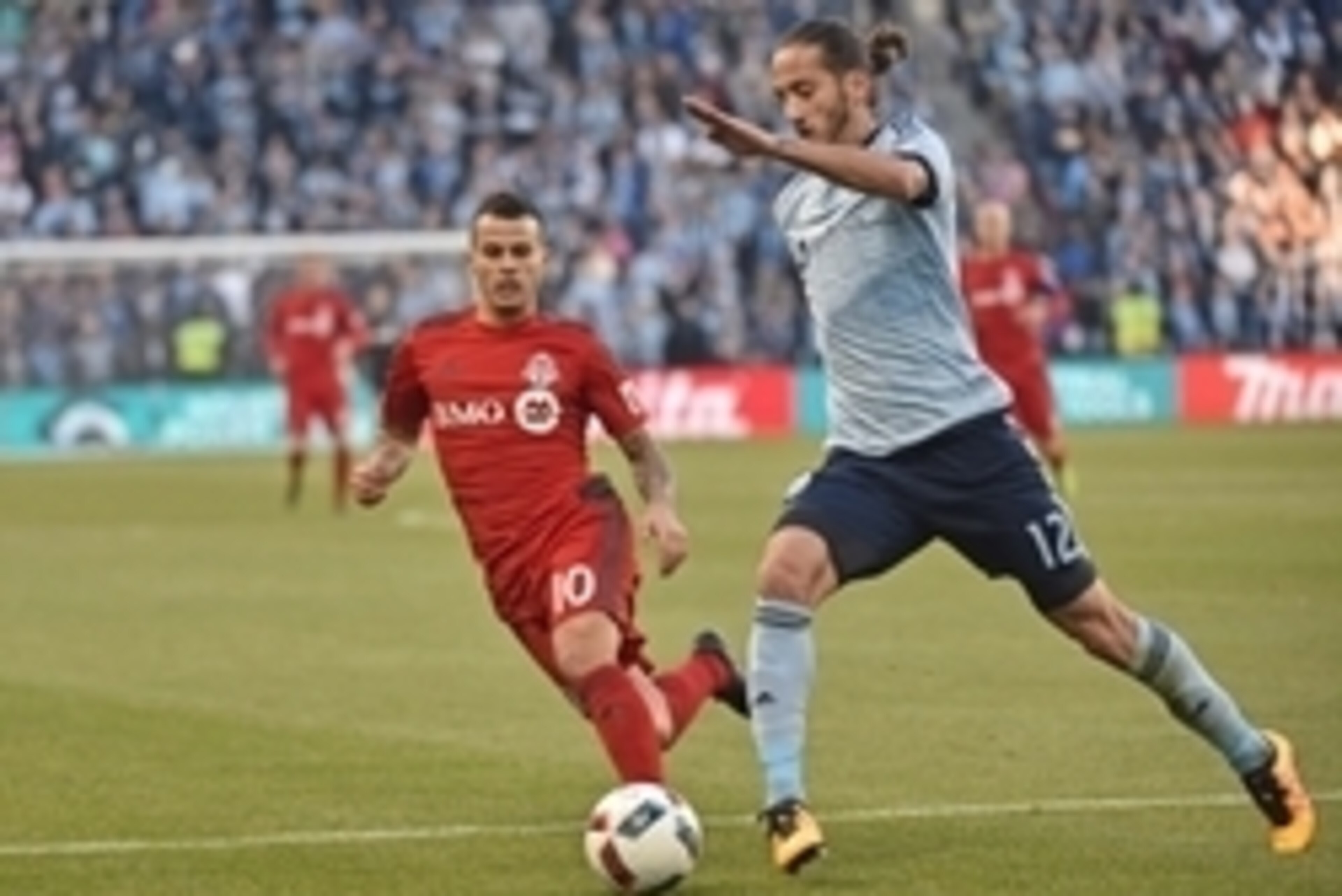 Mar 20, 2016; Kansas City, KS, USA; Sporting KC defender Nuno Coelho (12) dribbles the ball against Toronto FC forward Sebastian Giovinco (10) during the first half at Children's Mercy Park. Mandatory Credit: Peter G. Aiken-USA TODAY Sports