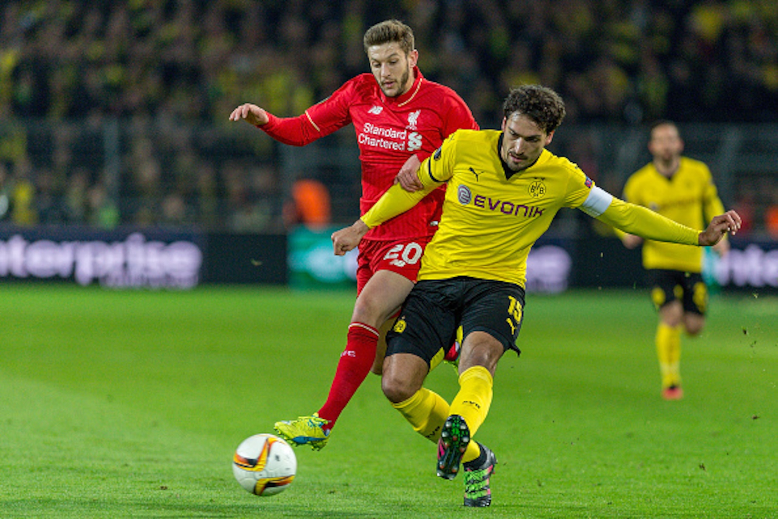 DORTMUND, GERMANY - APRIL 07: Defense Mats Hummels (15) of Borussia Dortmund passing the ball while Midfielder Adam Lallana (20) of FC Liverpool interfering at Signal Iduna Park during the UEFA Europa League quarter final first leg match between Borussia 