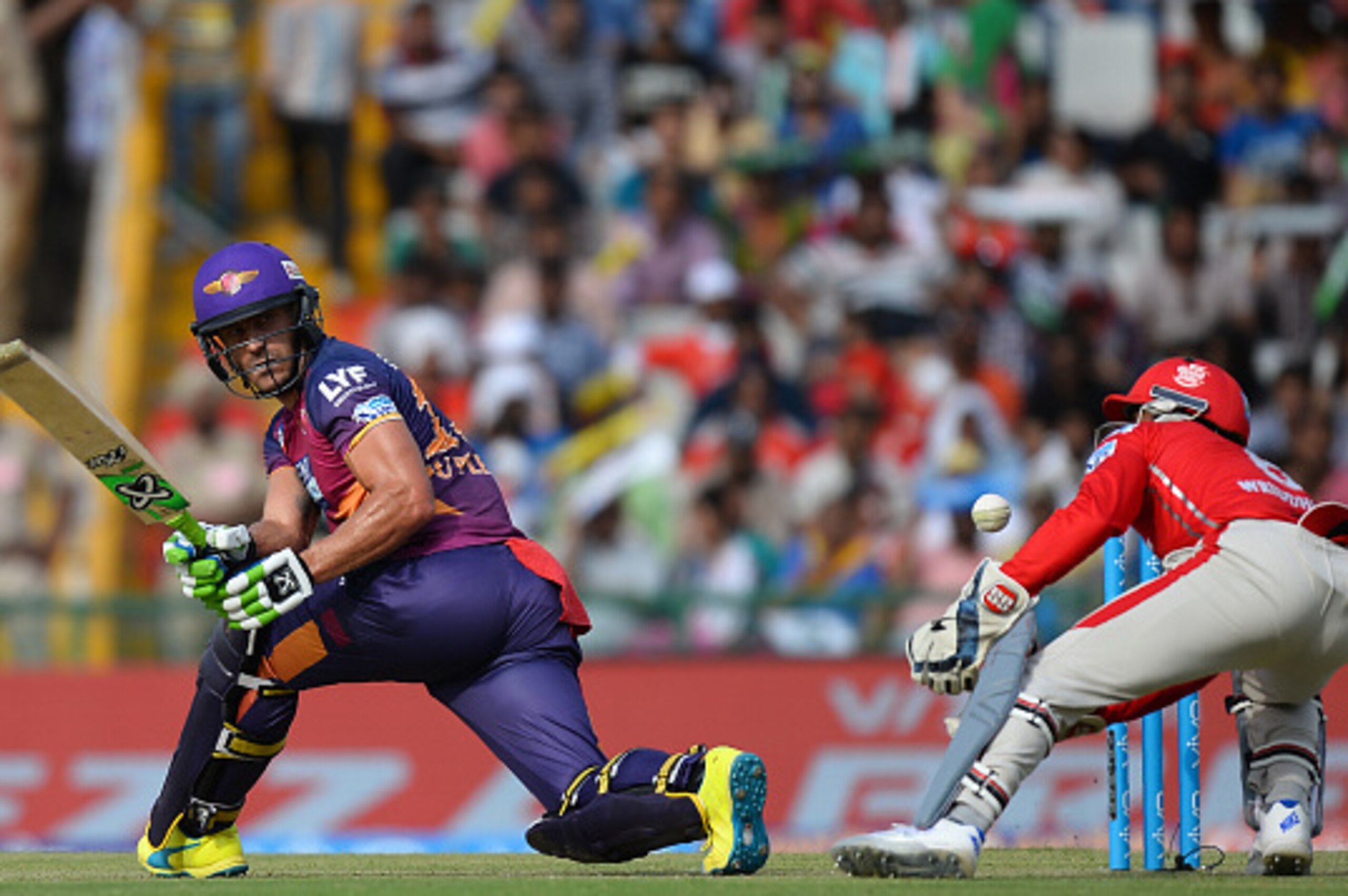 Rising Pune Supergiants batsman Faf Du Plessis(L)is watched by King's Xi Punjab wicketkeeper Wriddhiman Saha as he plays a shot during the 2016 Indian Premier League (IPL) Twenty20 cricket match between Rising Pune Supergiants and Kings XI Punjab at The P