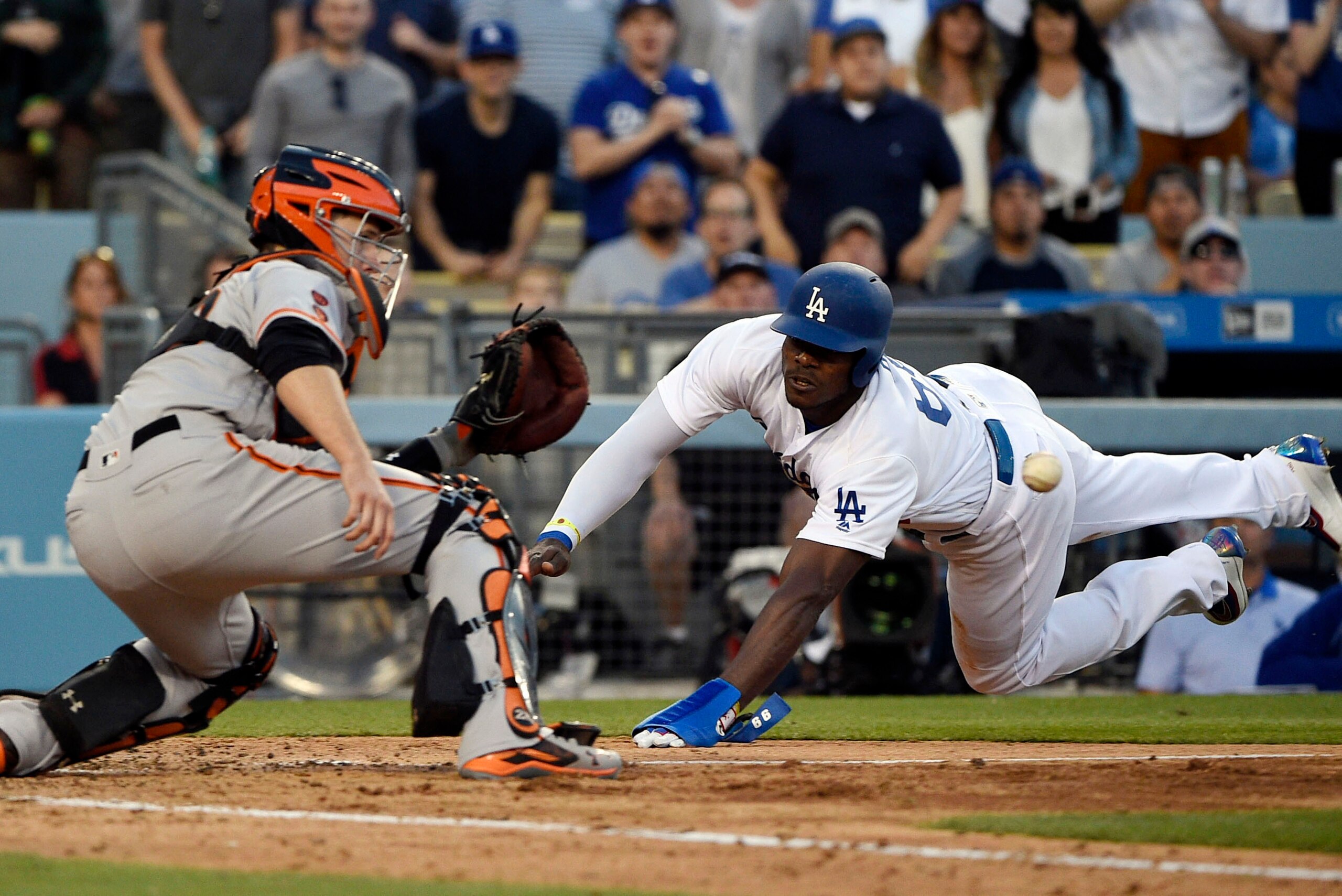 Apr 17, 2016; Los Angeles, CA, USA; Los Angeles Dodgers right fielder Yasiel Puig (66) dives into home as San Francisco Giants catcher Buster Posey (28) attempts to catch the ball during the seventh inning at Dodger Stadium. Mandatory Credit: Kelvin Kuo-U