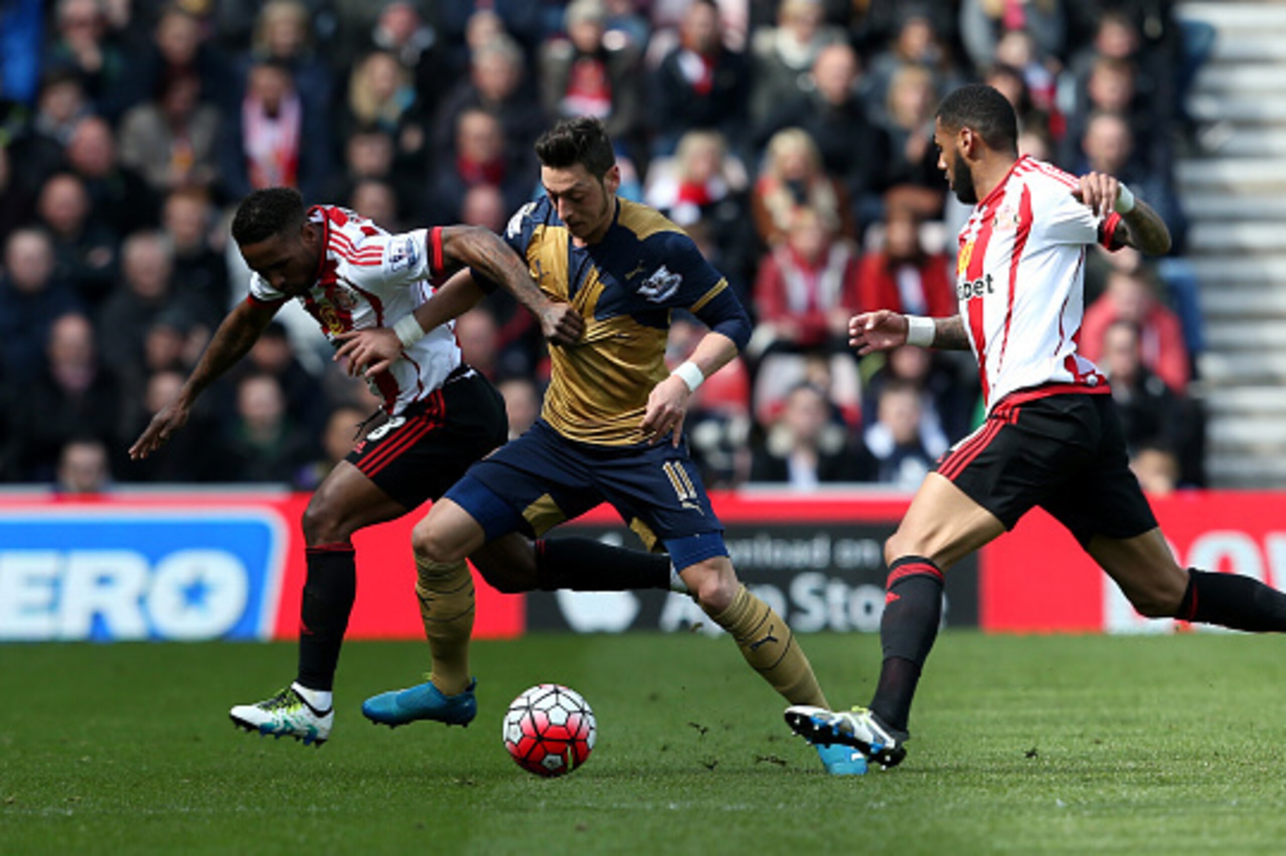 SUNDERLAND, ENGLAND - APRIL 24:  Mesut Ozil of Arsenal battles with Jermain Defoe (L) and Yann M'Vila of Sunderland (R) during the Barclays Premier League match between Sunderland and Arsenal at the Stadium of Light on April 24, 2016 in Sunderland, United