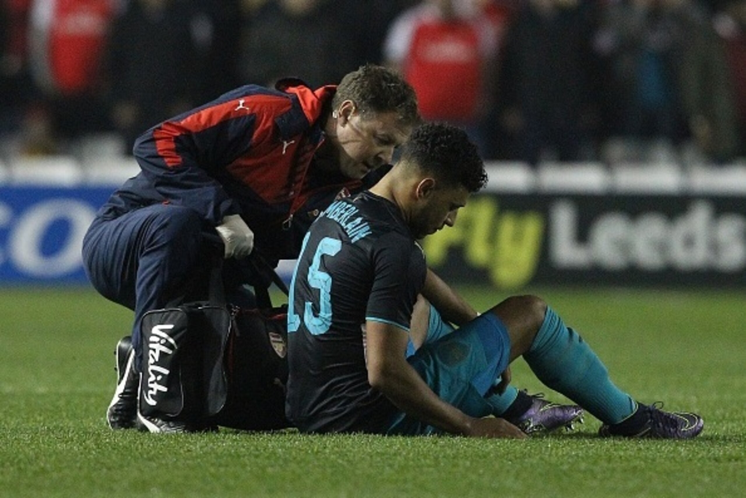 Arsenal's English striker Oxlade-Chamberlain (R) sits on the pitch injured before being substituted-off following a heavy tackle during the English League Cup fourth round football match between Sheffield Wednesday and Arsenal at The Hillsborough Stadium 