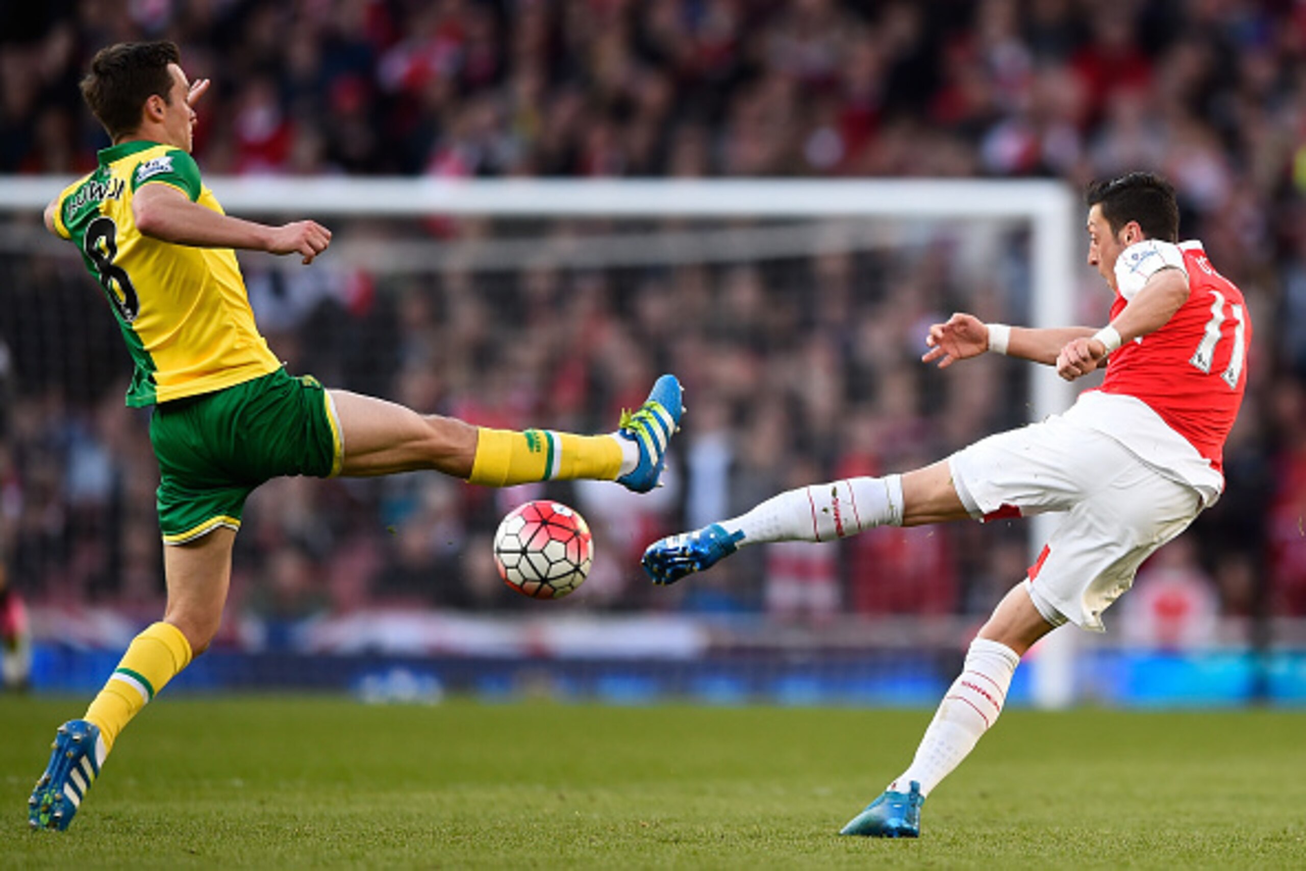 LONDON, ENGLAND - APRIL 30: Mesut Oezil of Arsenal makes a long range pass as he is challenged by Jonathan Howson of Norwich City during the Barclays Premier League match between Arsenal and Norwich City at The Emirates Stadium on April 30, 2016 in London