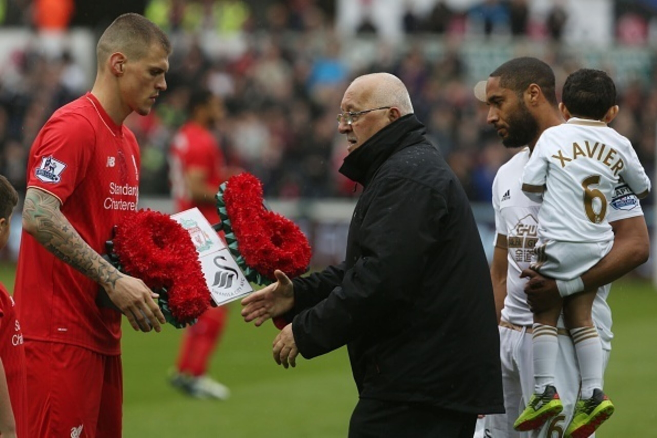 Team captains Liverpools Slovakian defender Martin Skrtel (L) and Swansea City's English-born Welsh defender Ashley Williams (R) present a wreath to Brian Devonside, father of Hillsborough victim Christopher Devonside, in memory of the 96 victims of the 1