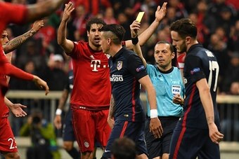 Turkish referee Cuneyt Cakir shows Atletico Madrid's Uruguayan defender Jose Maria Gimenez the yellow card during the UEFA Champions League semi-final, second-leg football match between FC Bayern Munich and Atletico Madrid in Munich, southern Germany, on 