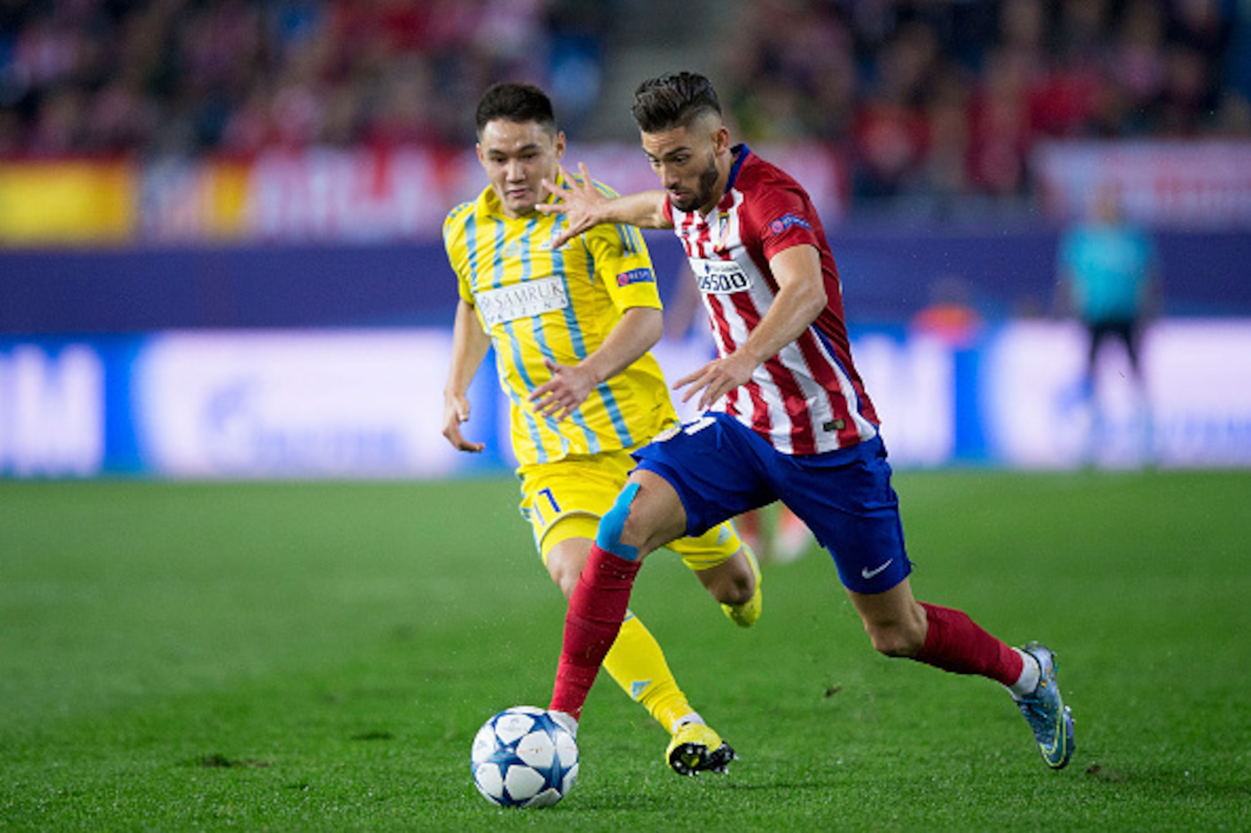MADRID, SPAIN - OCTOBER 21: Yannick Carrasco (R) of Atletico de Madrid competes for the ball with Serikzhan Muzhikov (L) of FC Astana during the UEFA Champions League Group C match between Club Atletico de Madrid and FC Astana at Vicente Calderon stadium 