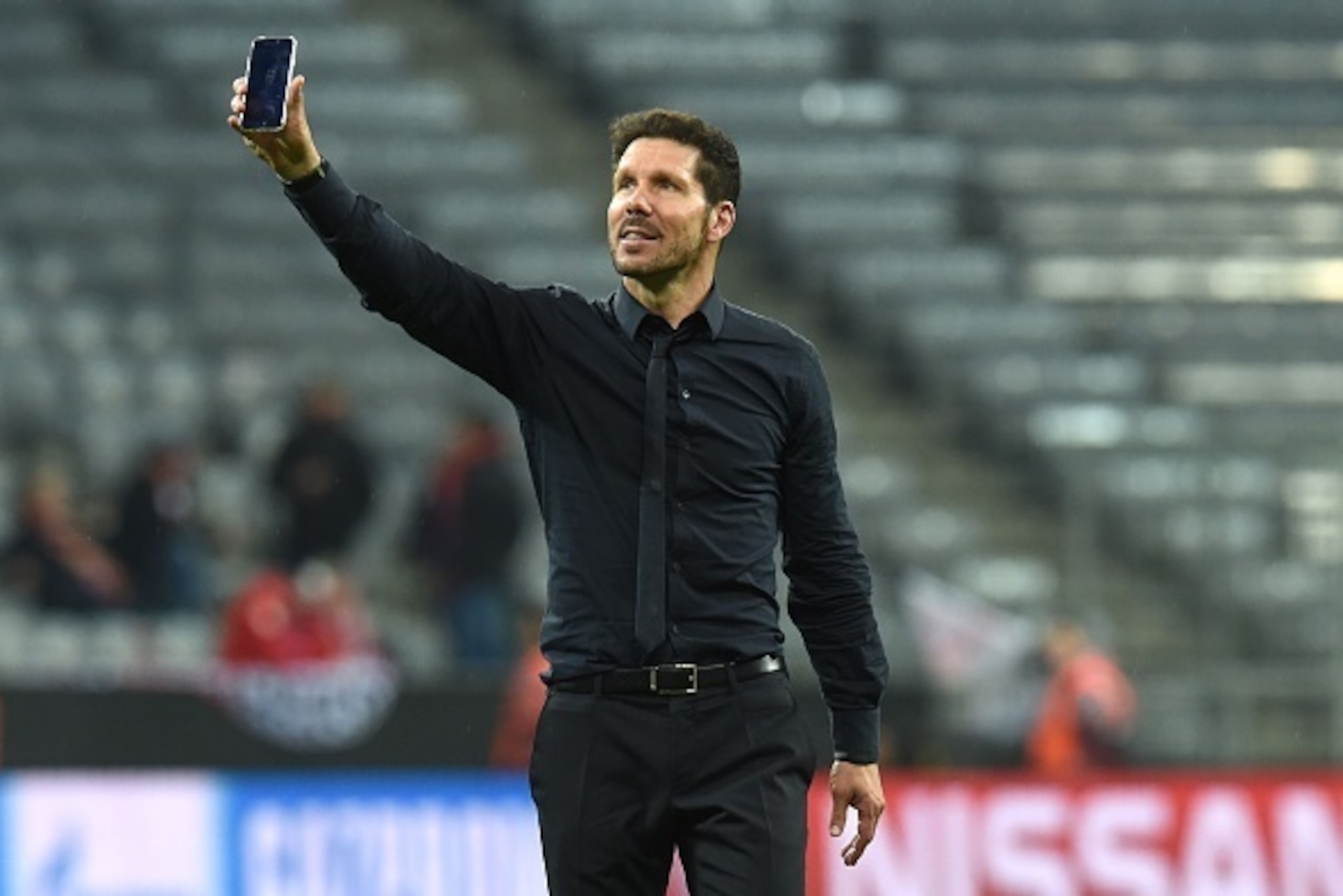 Atletico Madrid's Argentinian coach Diego Simeone uses his smartphone while celebrating  qualifying for the final after the UEFA Champions League semi-final, second-leg football match between FC Bayern Munich and Atletico Madrid in Munich, southern German