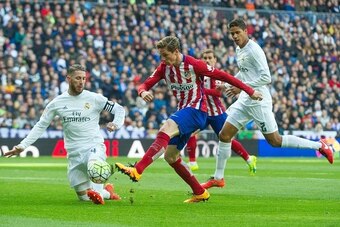 Real Madrid's defender Sergio Ramos (L) and Real Madrid's French defender Raphael Varane (R) vies with Atletico Madrid's forward Fernando Torres during the Spanish league football match Real Madrid CF vs Club Atletico de Madrid at the Santiago Bernabeu st