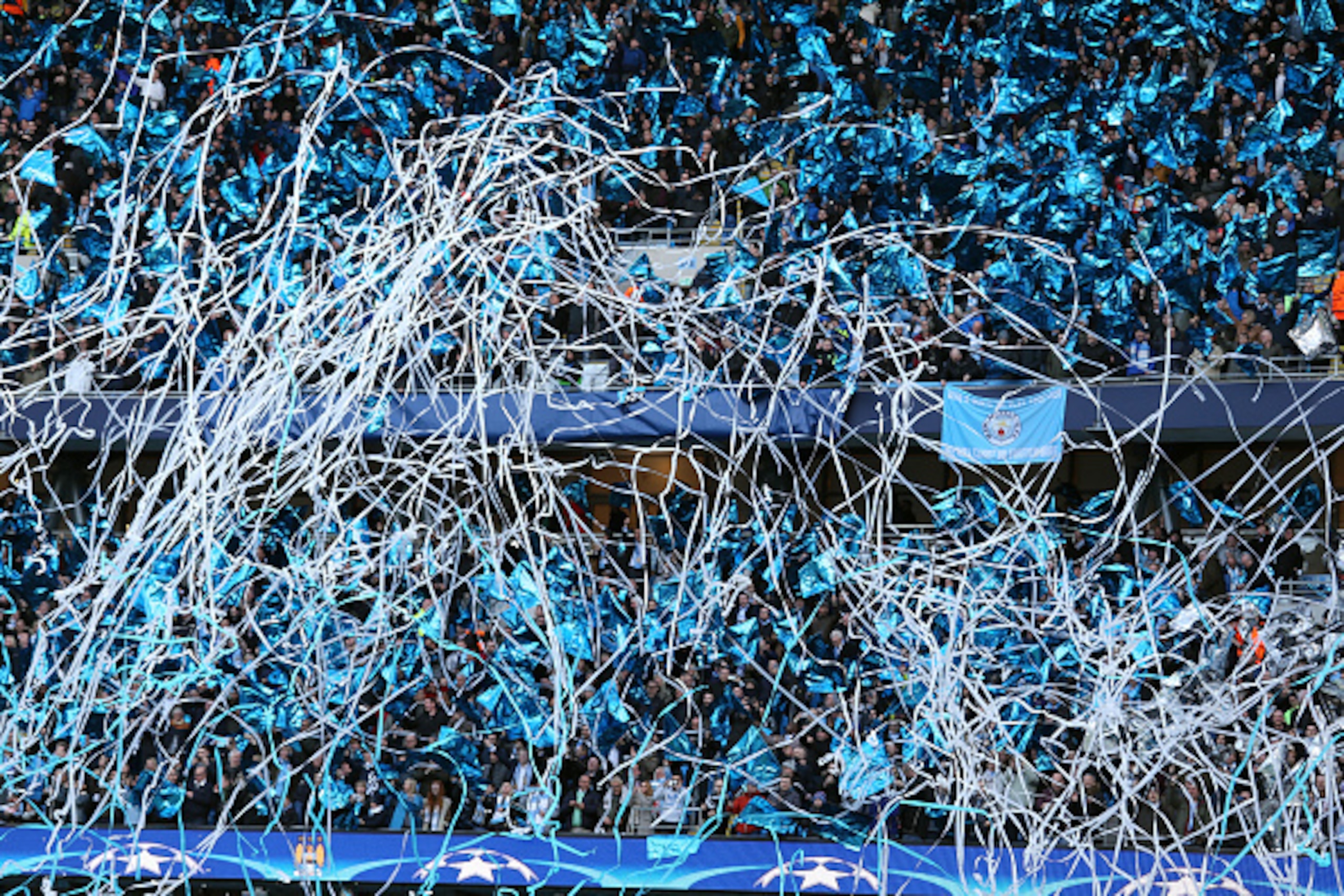 MANCHESTER, ENGLAND - APRIL 26: Fans of Manchester City wave flags and release streamers before the UEFA Champions League Semi Final first leg match between Manchester City FC and Real Madrid at the Etihad Stadium on April 26, 2016 in Manchester, United K MANCHESTER, ENGLAND - APRIL 26: Fans of Manchester City wave flags and release streamers before the UEFA Champions League Semi Final first leg match between Manchester City FC and Real Madrid at the Etihad Stadium on April 26, 2016 in Manchester, United K