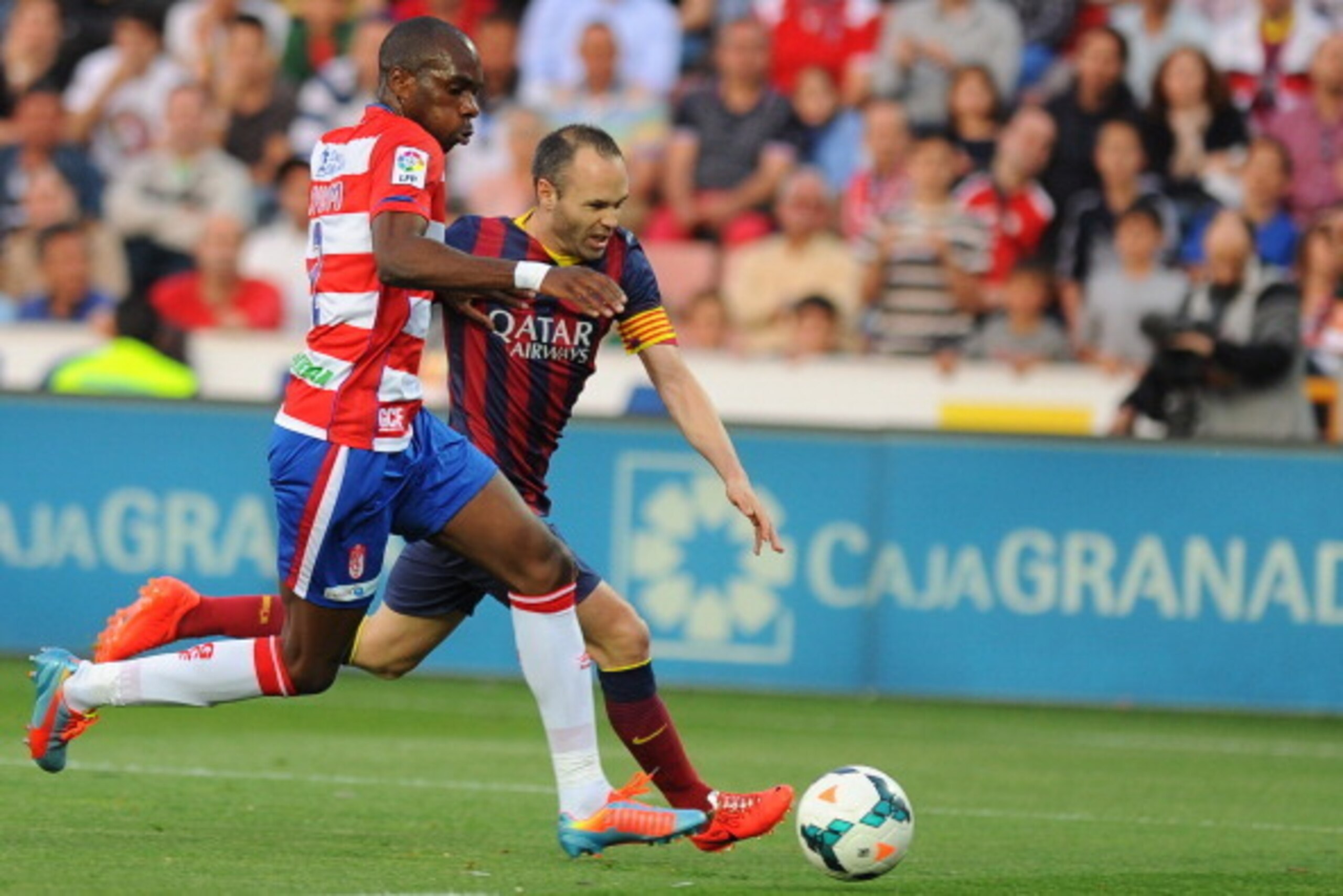 Granada's Cameroonian defender Allan Nyom (L) vies with Barcelona's midfielder Andres Iniesta during the Spanish league football match Granada CF vs FC Barcelona at the Nuevo Los Carmenes stadium in Granada on April 12, 2014.   AFP PHOTO/ JORGE GUERRERO  