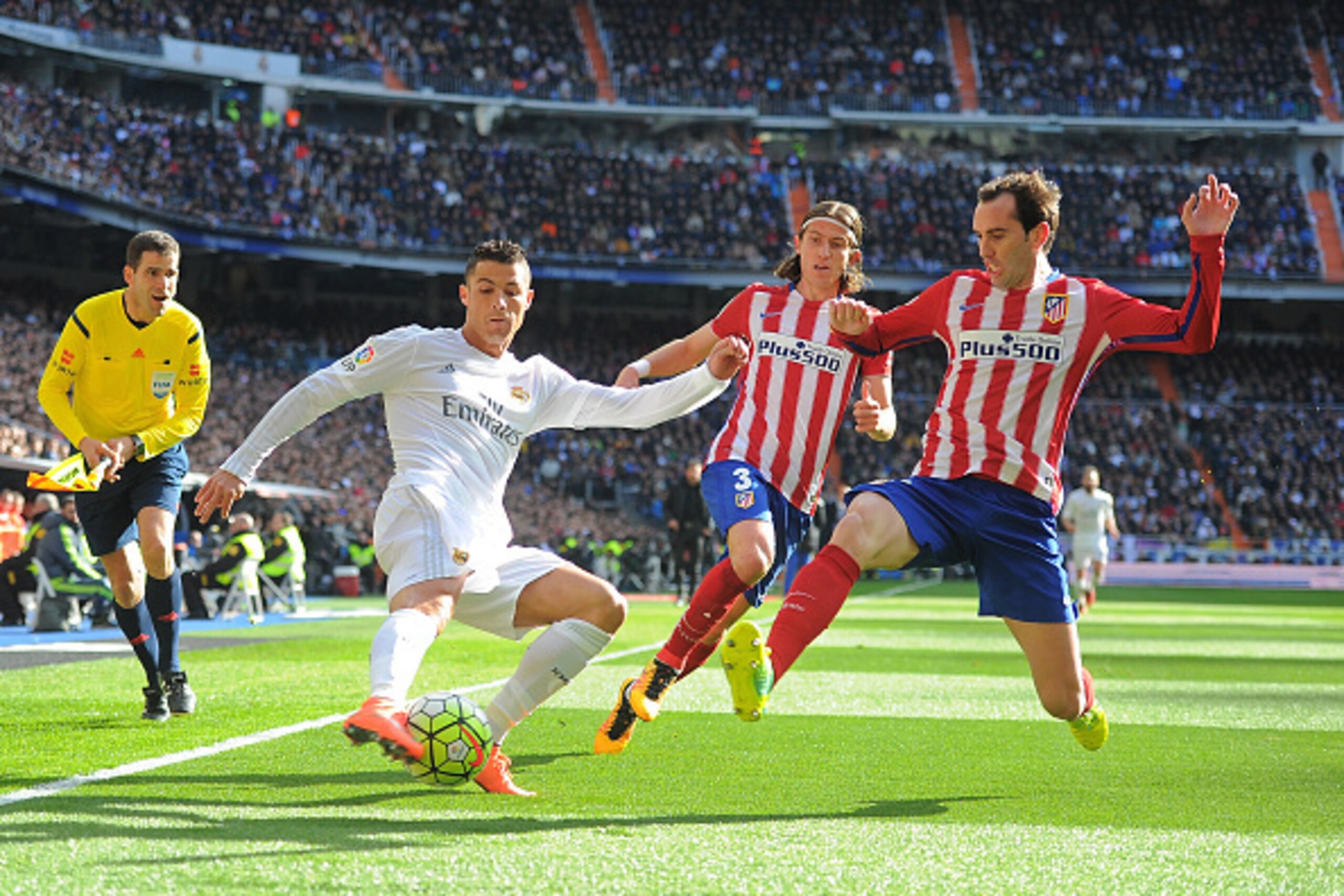 MADRID, SPAIN - FEBRUARY 27:   Cristiano Ronaldo of Real Madrid crosses the ball while being challenged by Diego Godin and Felipe Luis of Club Atletico de Madridduring the La Liga match between Real Madrid CF and Club Atletico de Madrid at Estadio Santiag