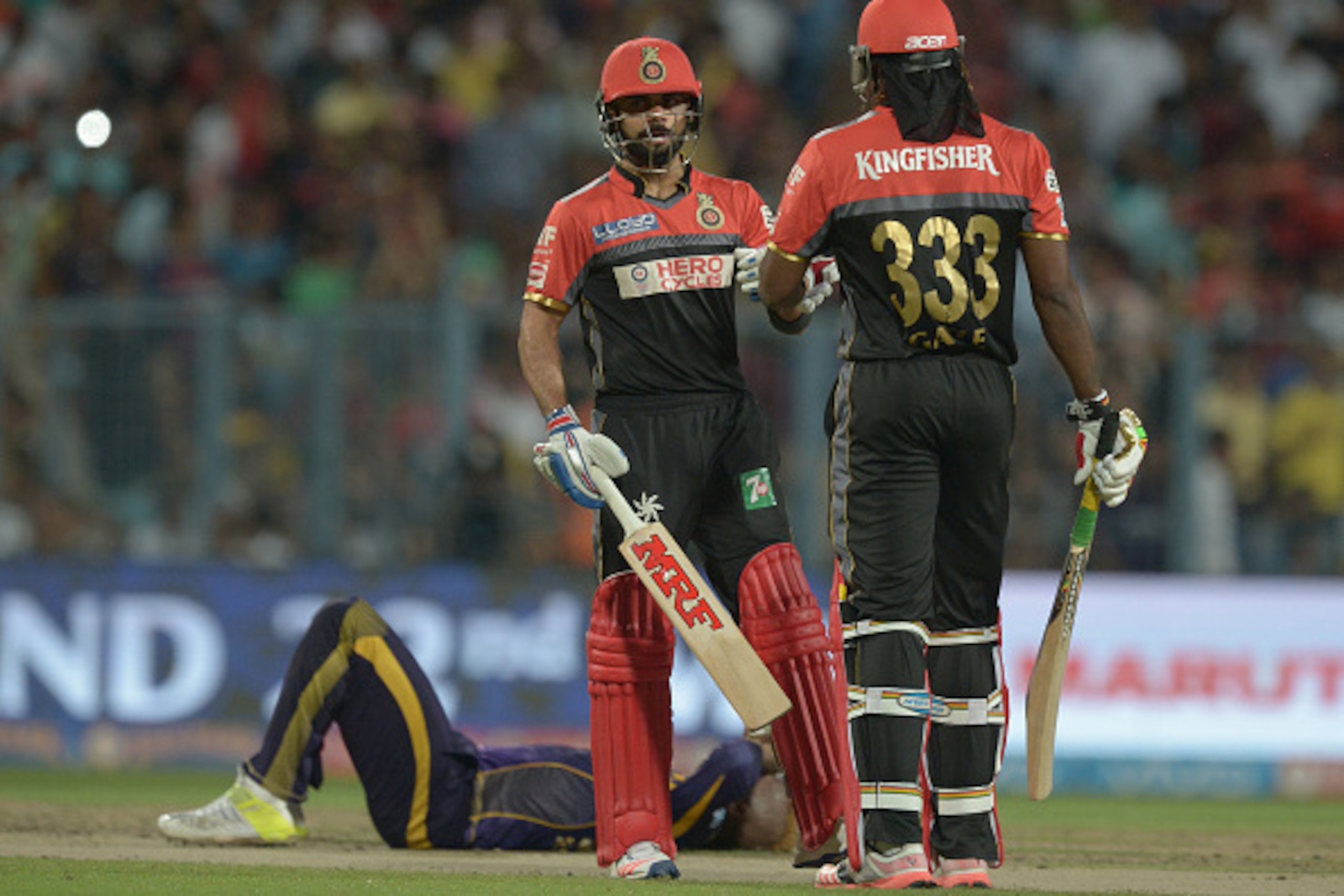 Royal Challengers Bangalore captain Virat Kohli (L) talks with Chris Gayle as Kolkata Knight Riders Andre Russell falls  during the 2016 Indian Premier League (IPL) Twenty20 cricket match between Kolkata Knight Riders and Royal Challengers Bangalore at th