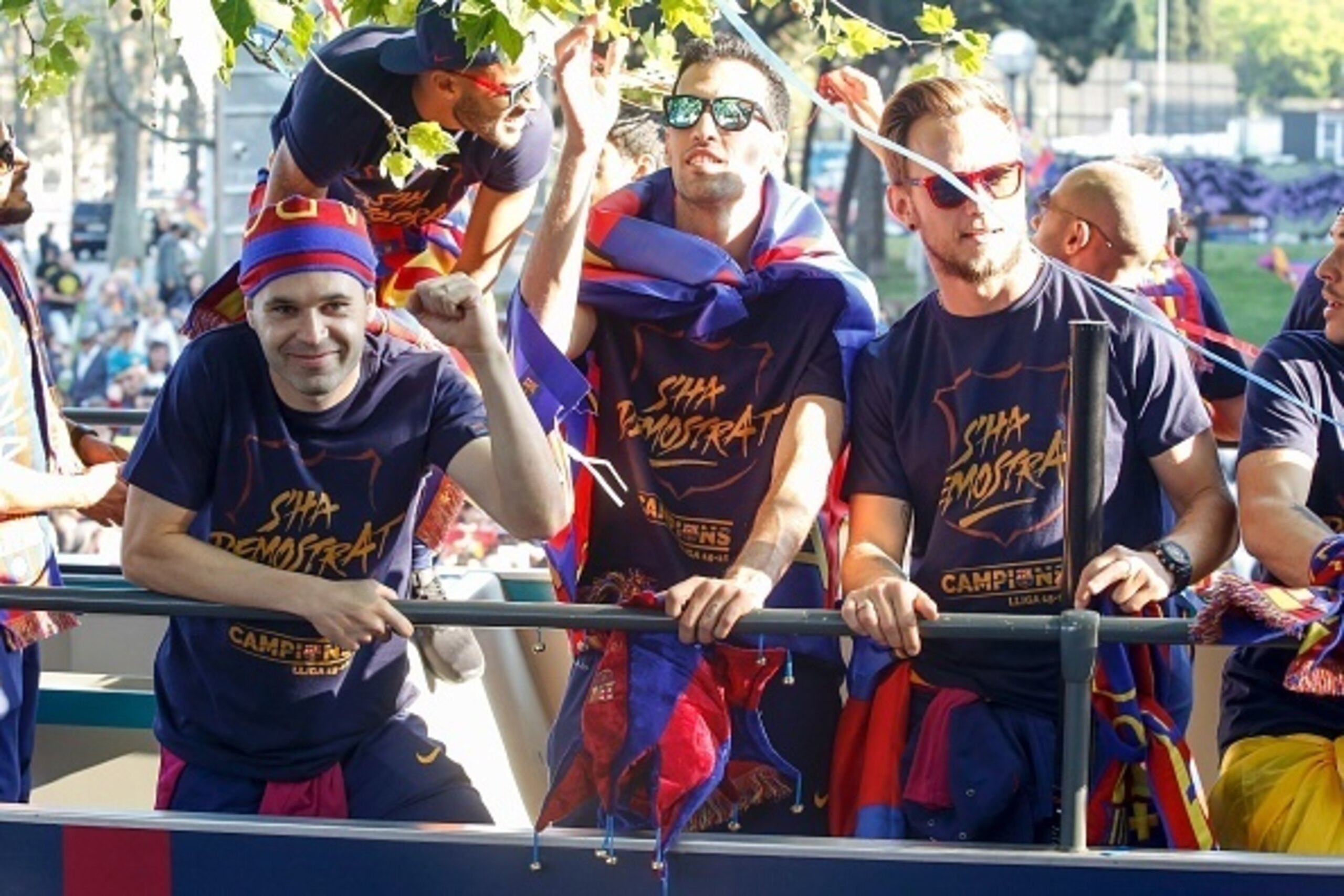 FC Barcelona's Spanish midfielder Andres Iniesta (L), Spanish midfielder Sergio Busquets (C) and Croatian midfielder Ivan Rakitic parade on a bus through the streets of Barcelona to celebrate their 24th La Liga title, in Barcelona, on May 15, 2016
Barcelo