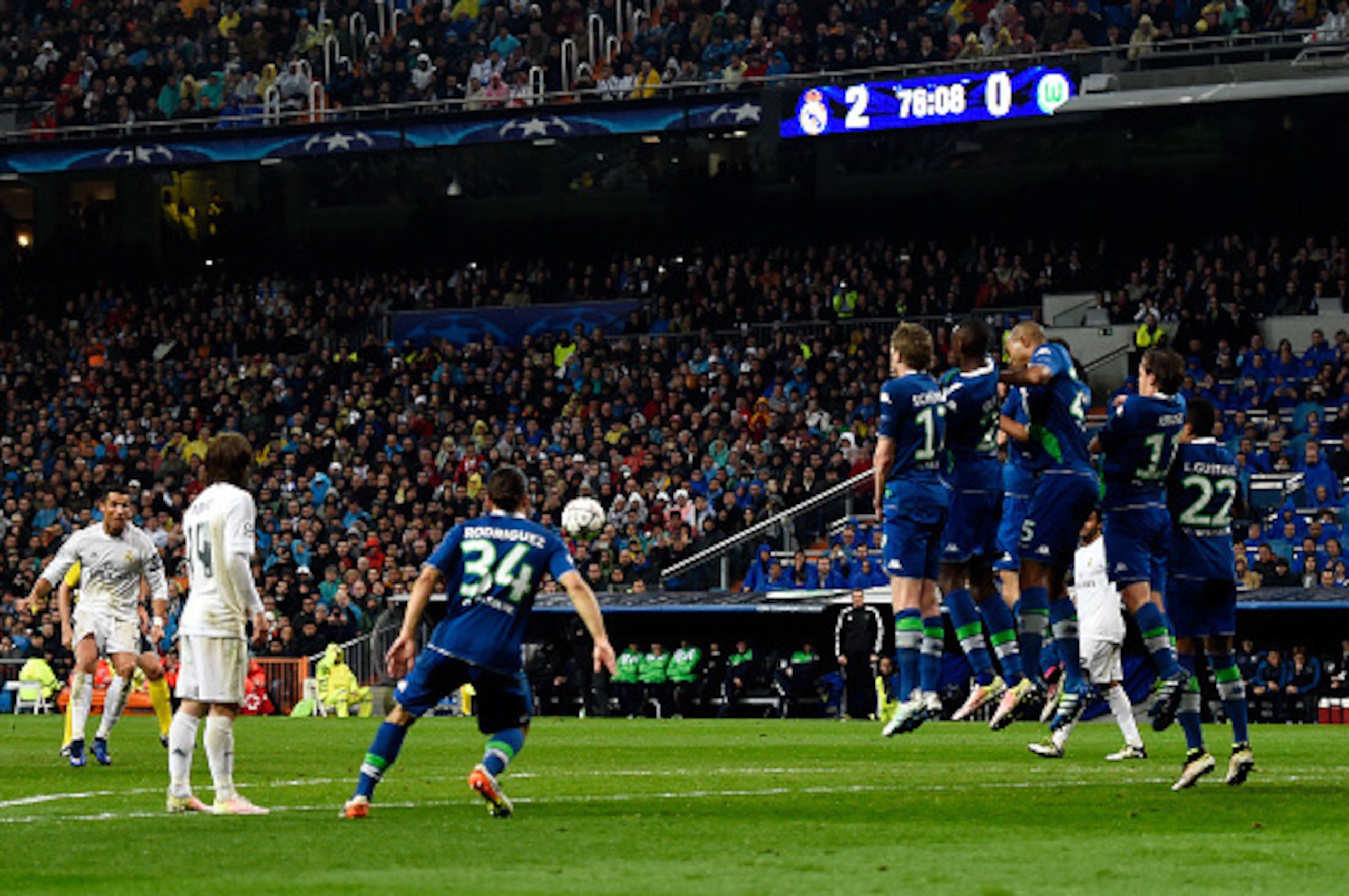 MADRID, SPAIN - APRIL 12:  Cristiano Ronaldo of Real Madrid (L) scores their their goal from a free kick and completes his hat trick during the UEFA Champions League quarter final second leg match between Real Madrid CF and VfL Wolfsburg at Estadio Santia
