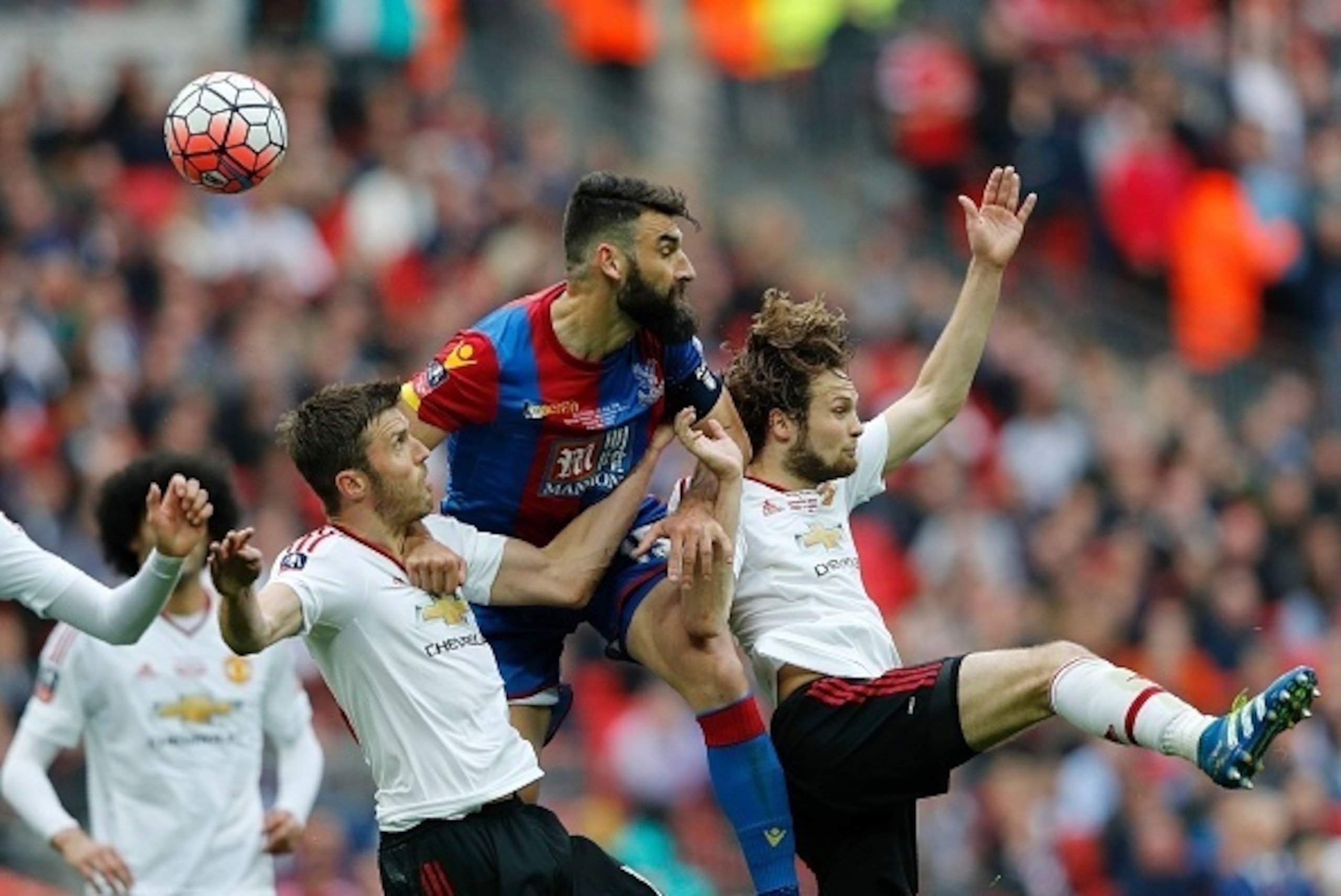 Crystal Palace's Australian midfielder Mile Jedinak (C) competes for the ball with Manchester United's Dutch midfielder Daley Blind (R) and Manchester United's English midfielder Michael Carrick during the English FA Cup final football match between Cryst