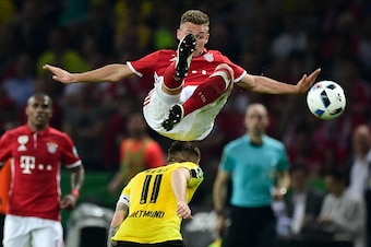 Bayern Munich's midfielder Joshua Kimmich (top) jumps over Dortmund's striker Marco Reus during the German Cup (DFB Pokal) final football match Bayern Munich vs Borussia Dortmund at the Olympic stadium in Berlin on May 21, 2016. / AFP / John MACDOUGALL / 