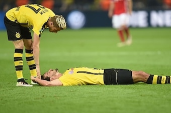 Dortmund's defender Erik Durm (L) stands next to Dortmund's defender Mats Hummels who lays on the pitch and grimaces in pain during the German Cup (DFB Pokal) final football match Bayern Munich vs Borussia Dortmund at the Olympic stadium in Berlin on May 