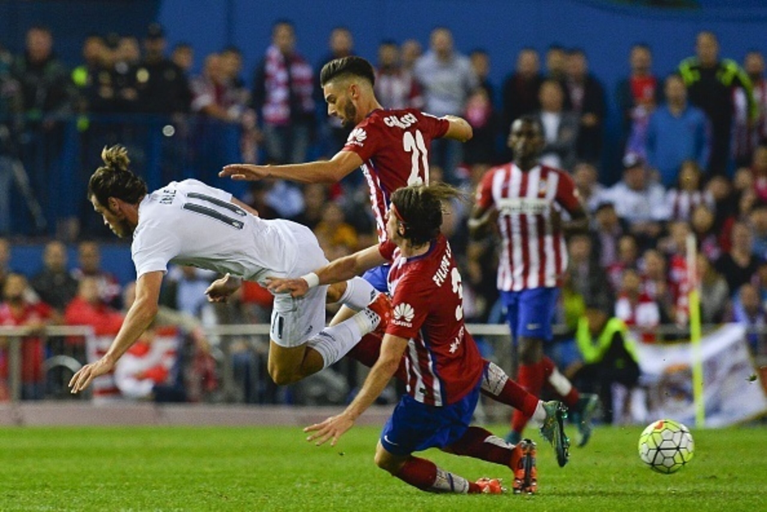 Real Madrid's Welsh forward Gareth Bale (L) falls past Atletico Madrid's Belgian midfielder Yannick Ferreira Carrasco (C) and Atletico Madrid's Brazilian defender Filipe Luis during the Spanish league football match Club Atletico de Madrid vs Real Madrid 