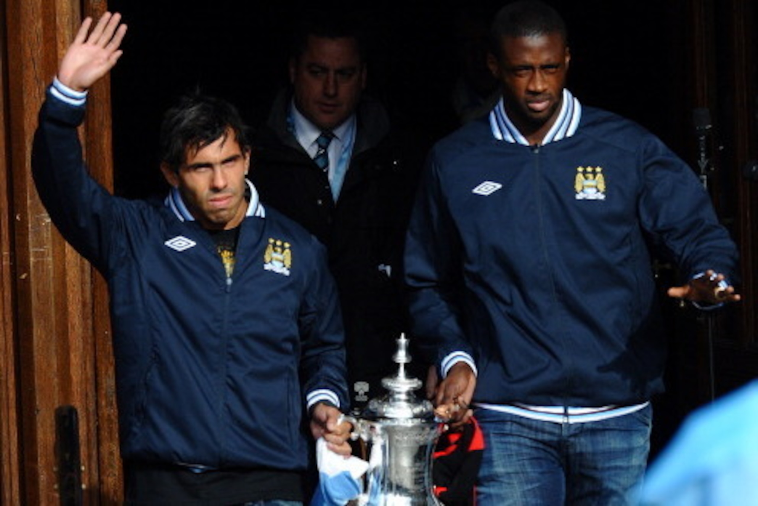 Manchester City's Argentinian forward Carlos Tevez (L) and Manchester City's Ivorian defender Yaya Toure (R) leave Manchester Town Hall carrying the FA Cup in Manchester, north west England, on May 23, 2011 for an open top bus tour of the city. Manchester
