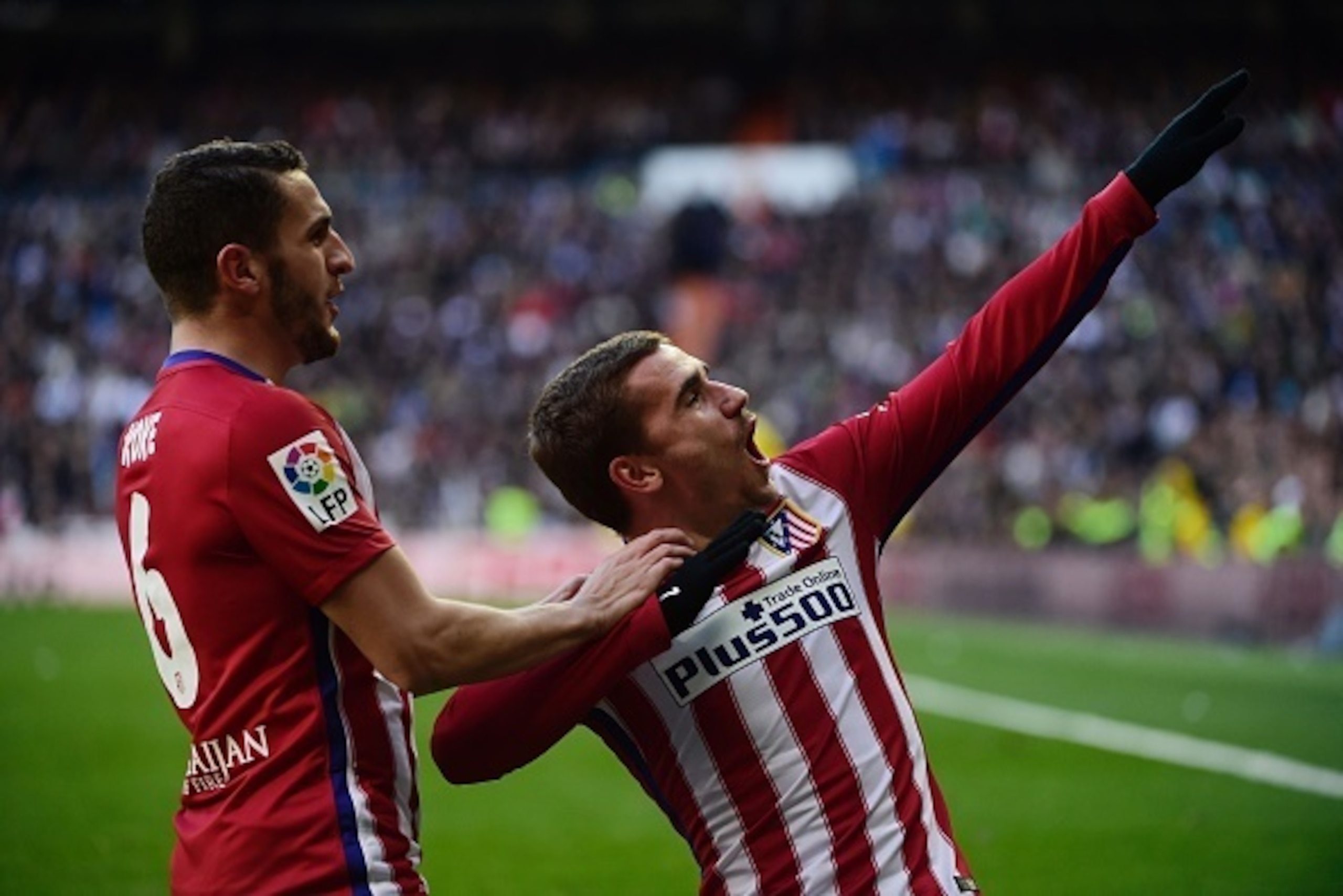 Atletico Madrid's French forward Antoine Griezmann (R) celebrates with Atletico Madrid's midfielder Koke after scoring during the Spanish league football match Real Madrid CF vs Atletico de Madrid at the Santiago Bernabeu stadium in Madrid on February 27,