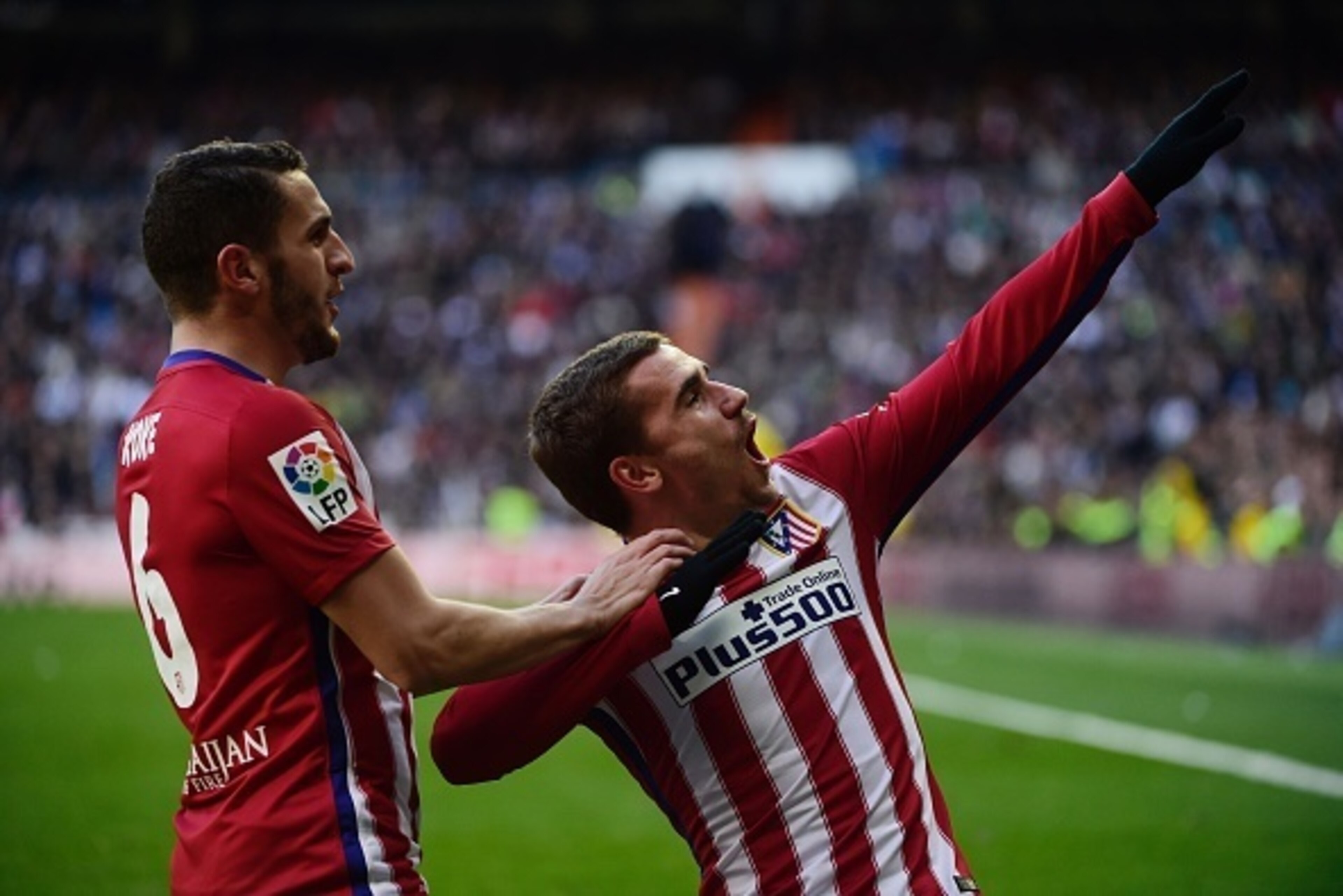 Atletico Madrid's French forward Antoine Griezmann (R) celebrates with Atletico Madrid's midfielder Koke after scoring during the Spanish league football match Real Madrid CF vs Atletico de Madrid at the Santiago Bernabeu stadium in Madrid on February 27,