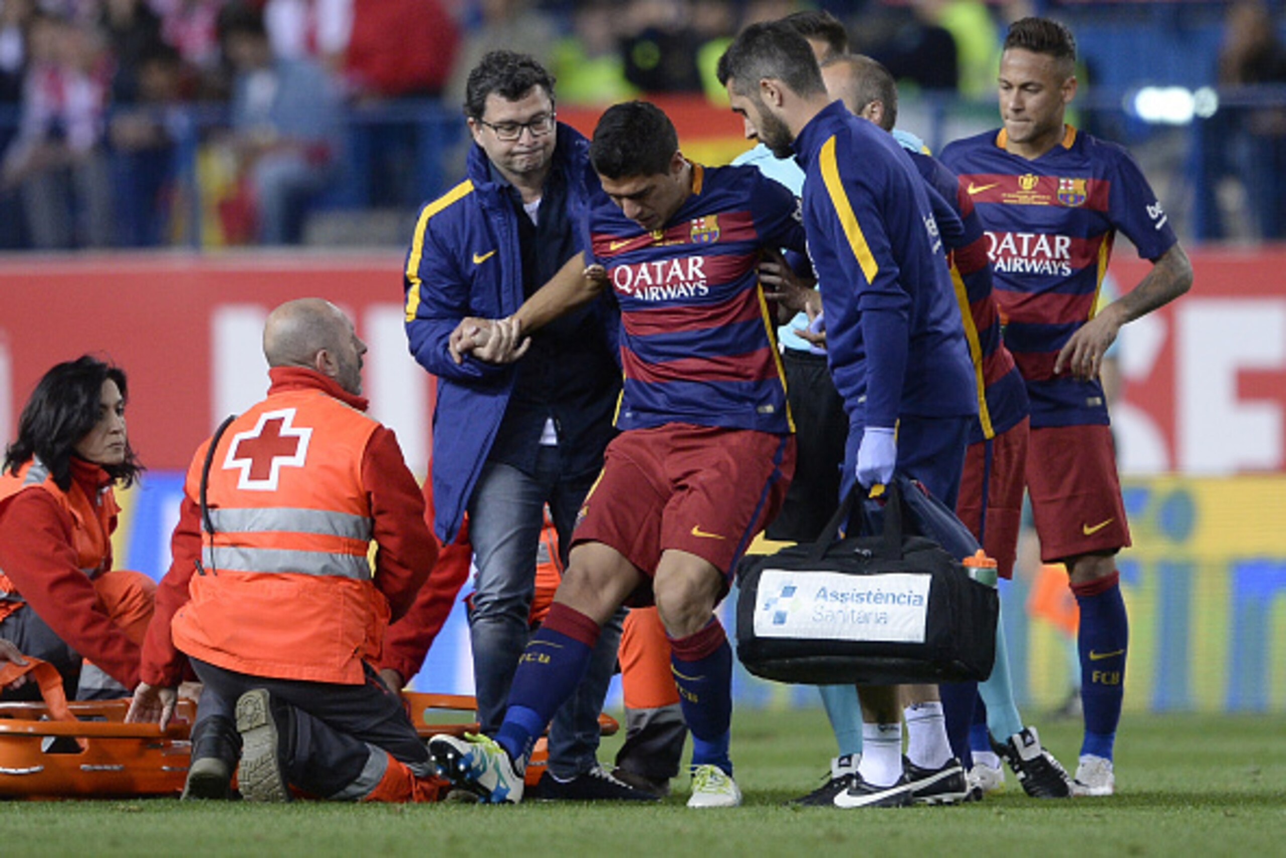 TOPSHOT - Barcelona's Uruguayan forward Luis Suarez (C) is assited after being injured beside Barcelona's Argentinian forward Lionel Messi during the Spanish 'Copa del Rey' (King's Cup) final match FC Barcelona vs Sevilla FC at the Vicente Calderon stadiu