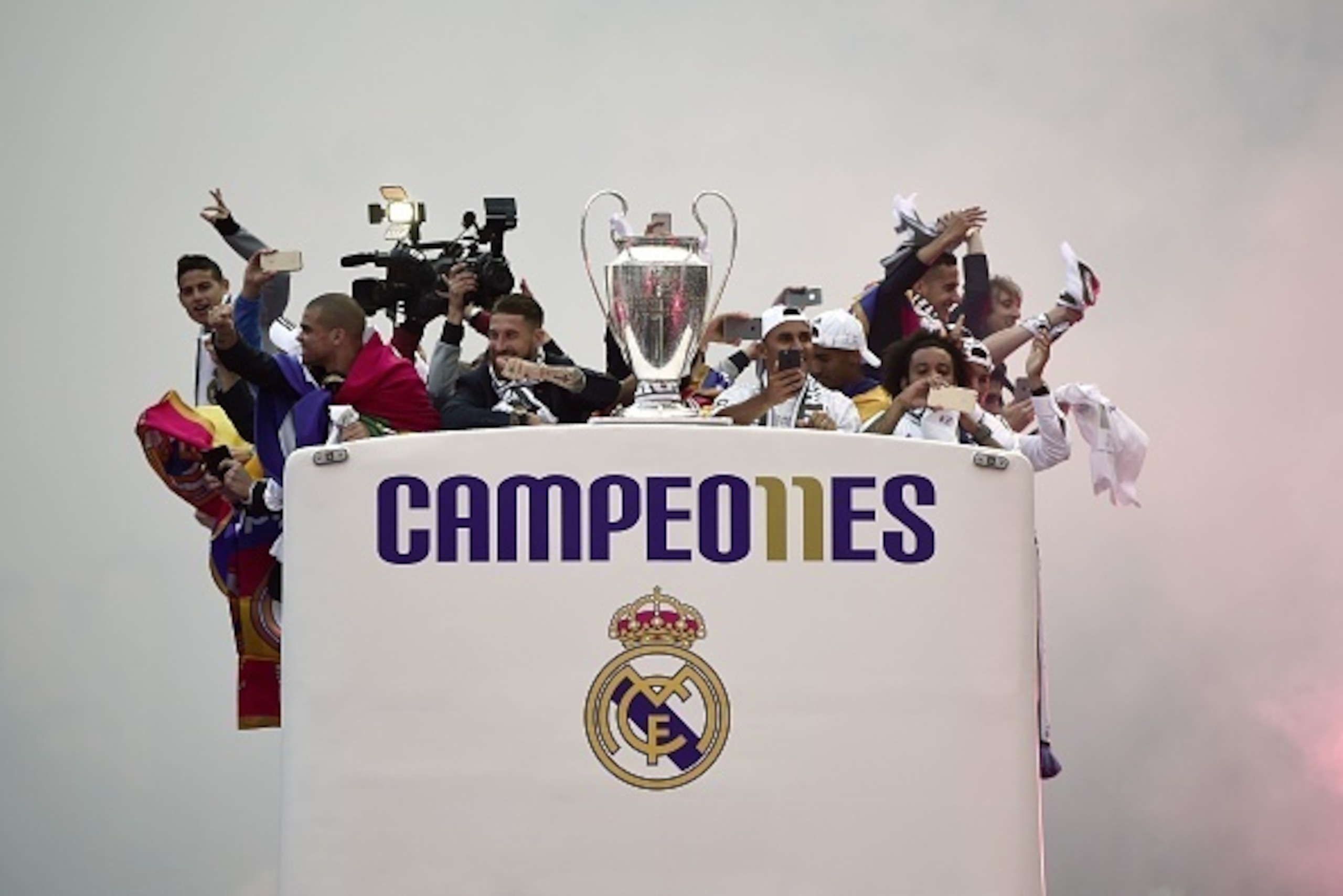 TOPSHOT - Real Madrid players hold up the trophy celebrating the team's win as they arrive by bus on Plaza Cibeles in Madrid on May 29, 2016 after the UEFA Champions League final foobtall match between Real Madrid CF, Club Atletico de Madrid held in Milan