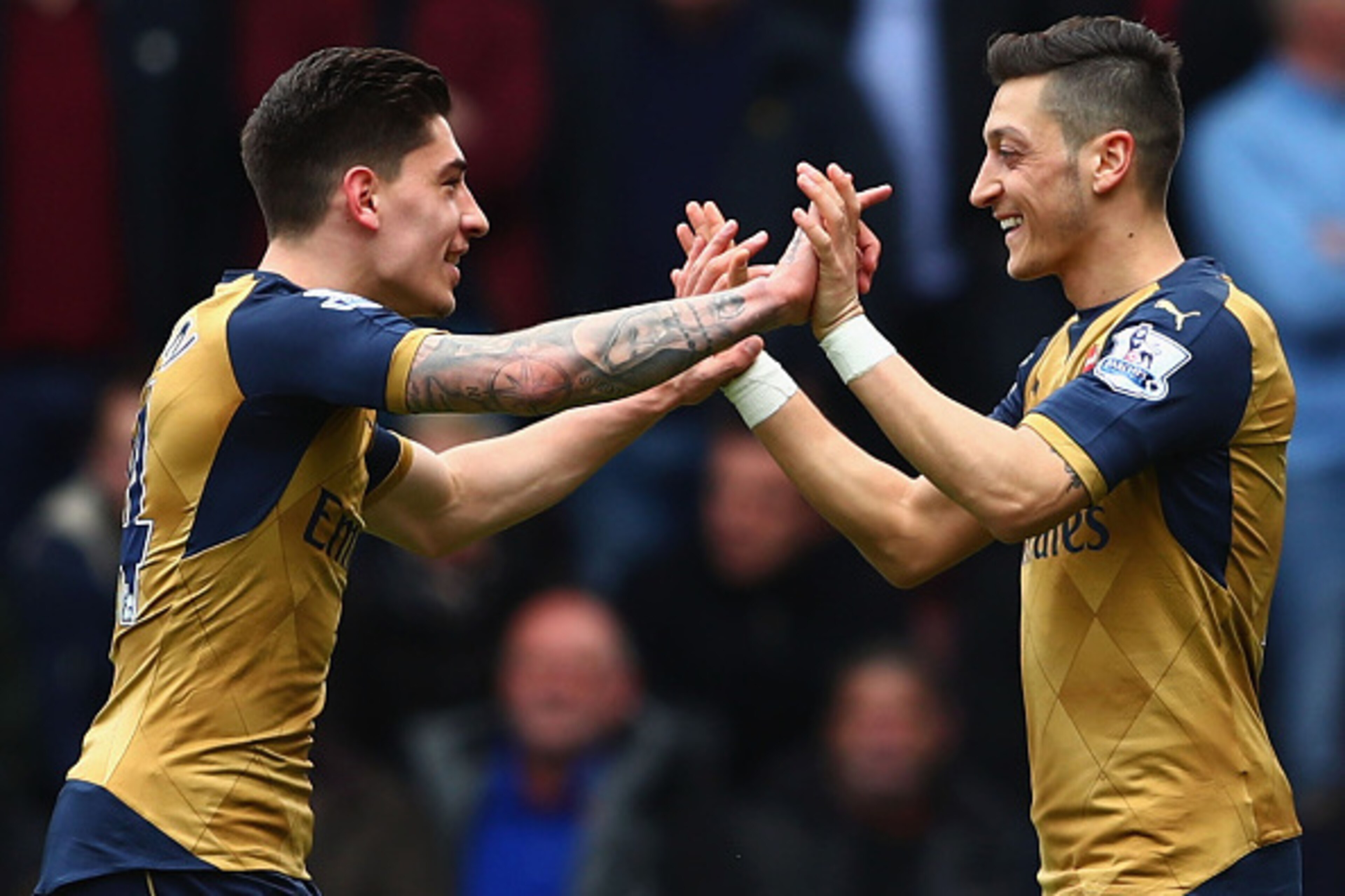 LONDON, UNITED KINGDOM - APRIL 09:  Mesut Ozil (R) of Arsenal celebrates scoring his team's first goal with his team mate Hector Bellerin (L) during the Barclays Premier League match between West Ham United and Arsenal at the Boleyn Ground on April 9, 201