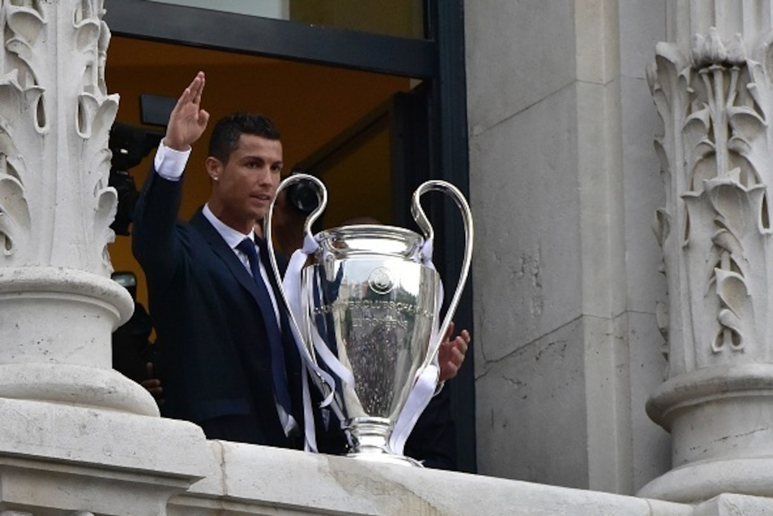 Real Madrid's Portuguese forward Cristiano Ronaldo waves as he shows the trophy from Madrid town hall's balcony on May 29, 2016 the day after winning the UEFA Champions League final foobtall match against Club Atletico de Madrid, held in Milan, Italy on M