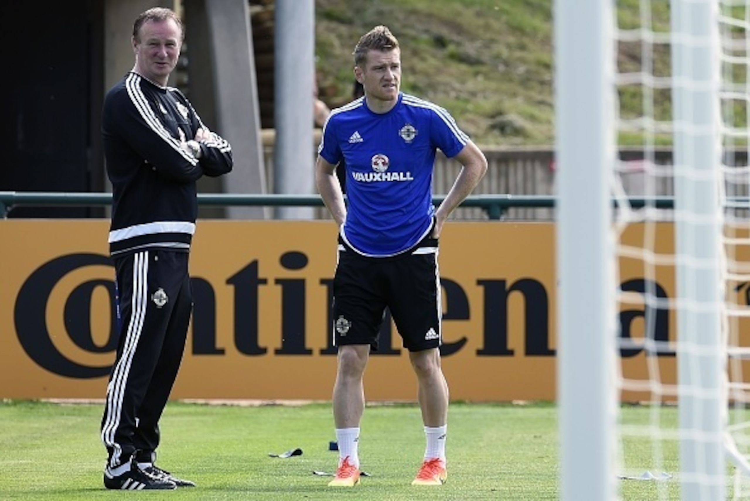Northern Ireland's captain Steven Davis (L) and coach Michael O'Neill (L) attend a training session while water spray at their training ground in Saint George de Reneins on June 6, 2016 during the Euro 2016 football tournament.   / AFP / PHILIPPE DESMAZES