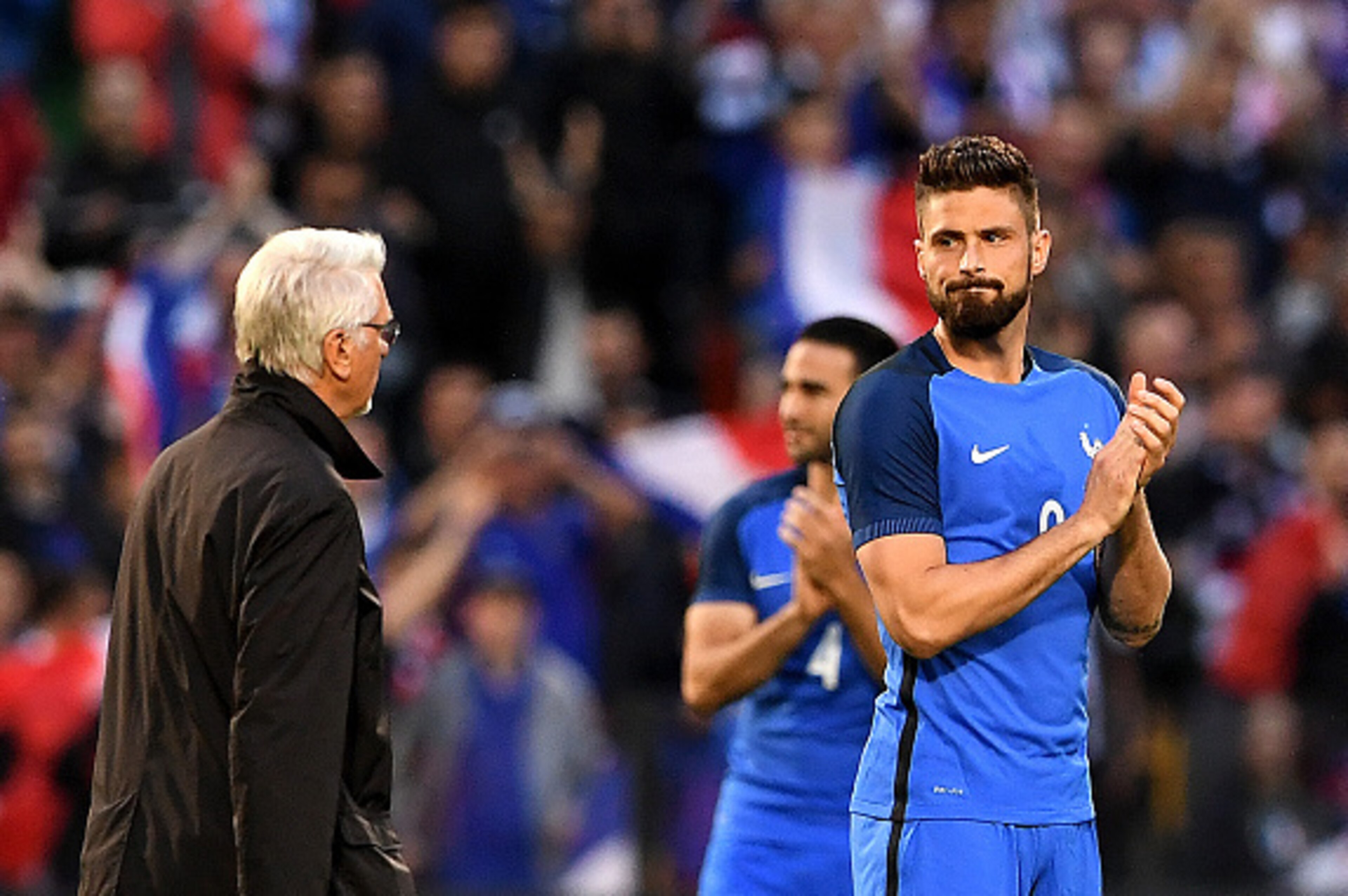 French natinal football team former head coach and 1998 FIFA World Cup winner, Aime Jacquet (L) passes next to France's forward Olivier Giroud prior to the friendly football match between France and Scotland, at the St Symphorien Stadium in Longeville-lès