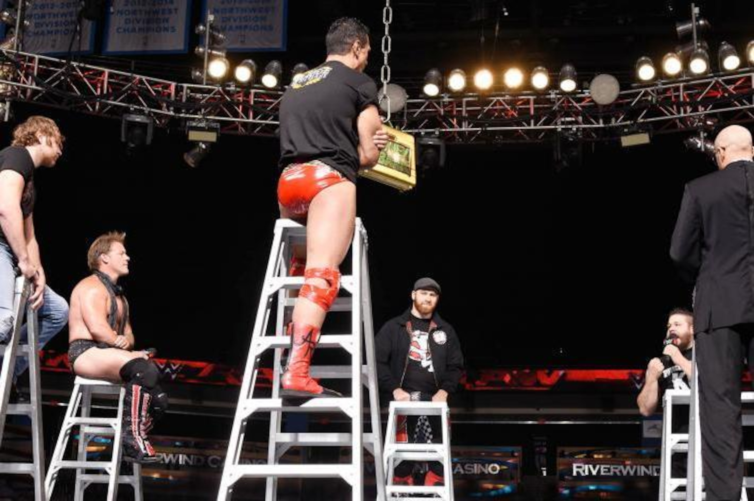 The Money in the Bank participants all bicker from atop ladders.