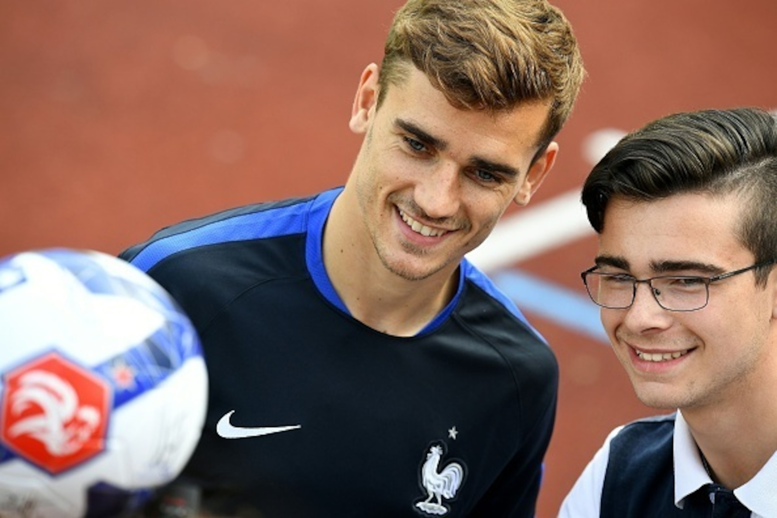 France's forward Antoine Griezmann (L) poses with a fan before a training session at their training ground in Clairefontaine-en-Yvelines, southwest of Paris, on June 6, 2016, ahead of the beginning of the Euro 2016 football tournament. / AFP / FRANCK FIFE