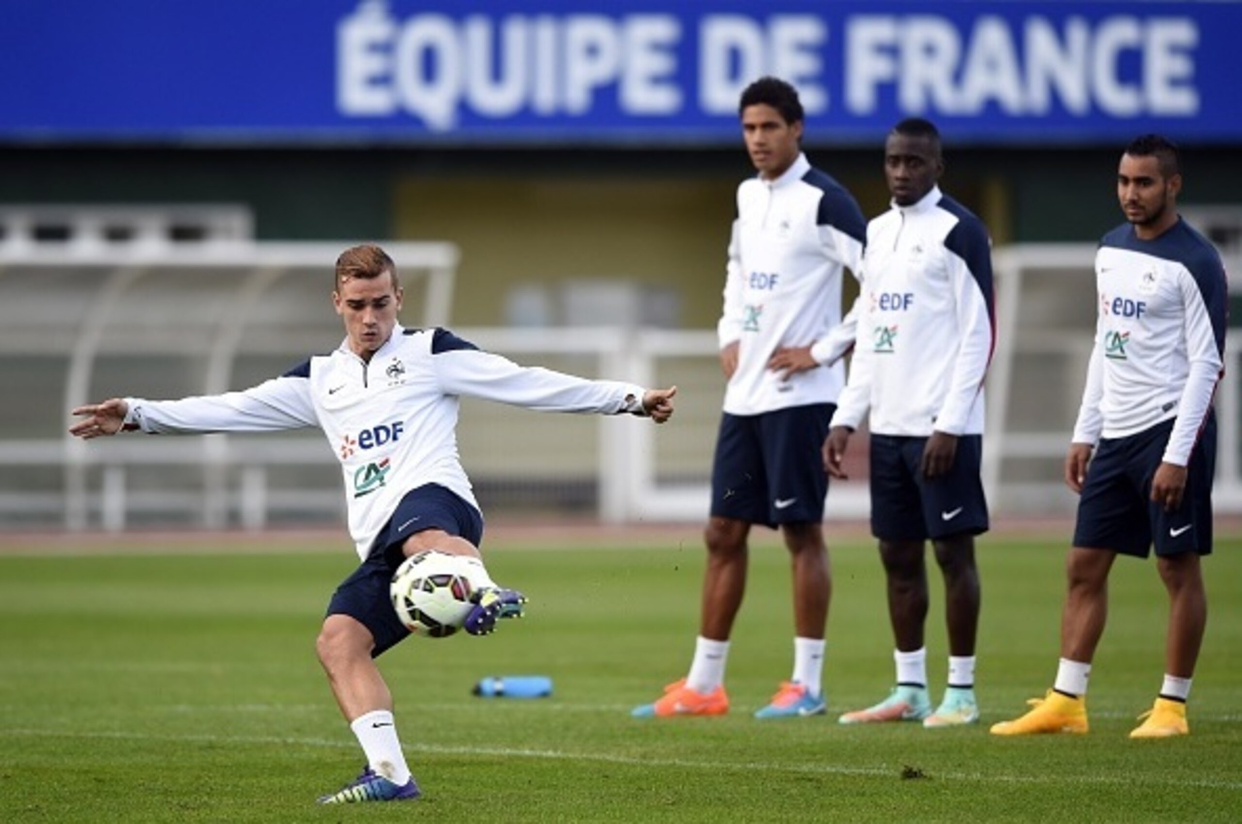 (LtoR) France's forward Antoine Griezmann kicks the ball in front France's defender Raphael Varane, France's midfielder Blaise Matuidi  and France's forward Dimitri Payet during a training session in Clairefontaine-en-Yvelines on October 9, 2014 ahead of