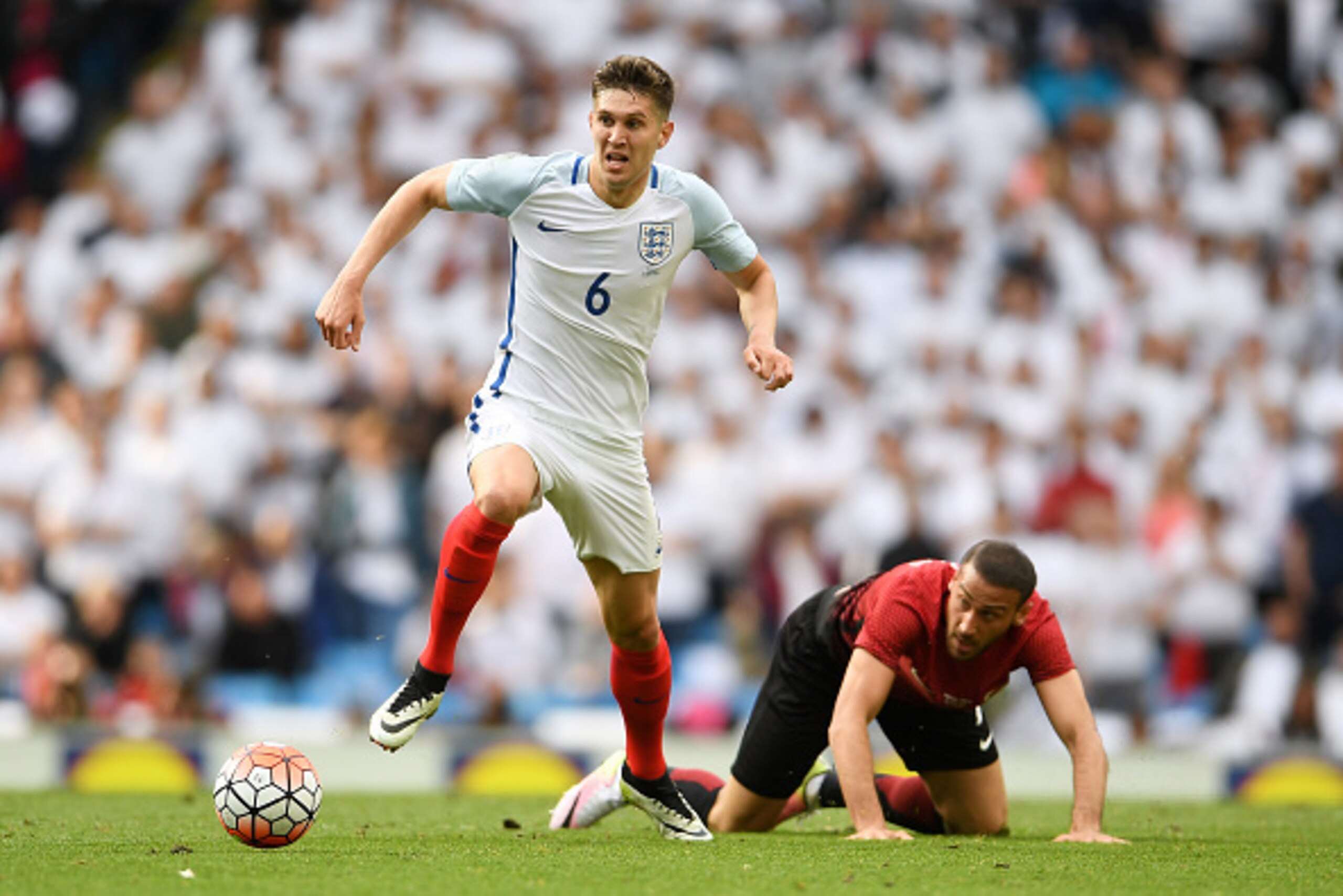MANCHESTER, ENGLAND - MAY 22:  John Stones of England battles for the ball with Cenk Tosun of Turkey during the International Friendly match between England and Turkey at Etihad Stadium on May 22, 2016 in Manchester, England.  (Photo by Laurence Griffiths