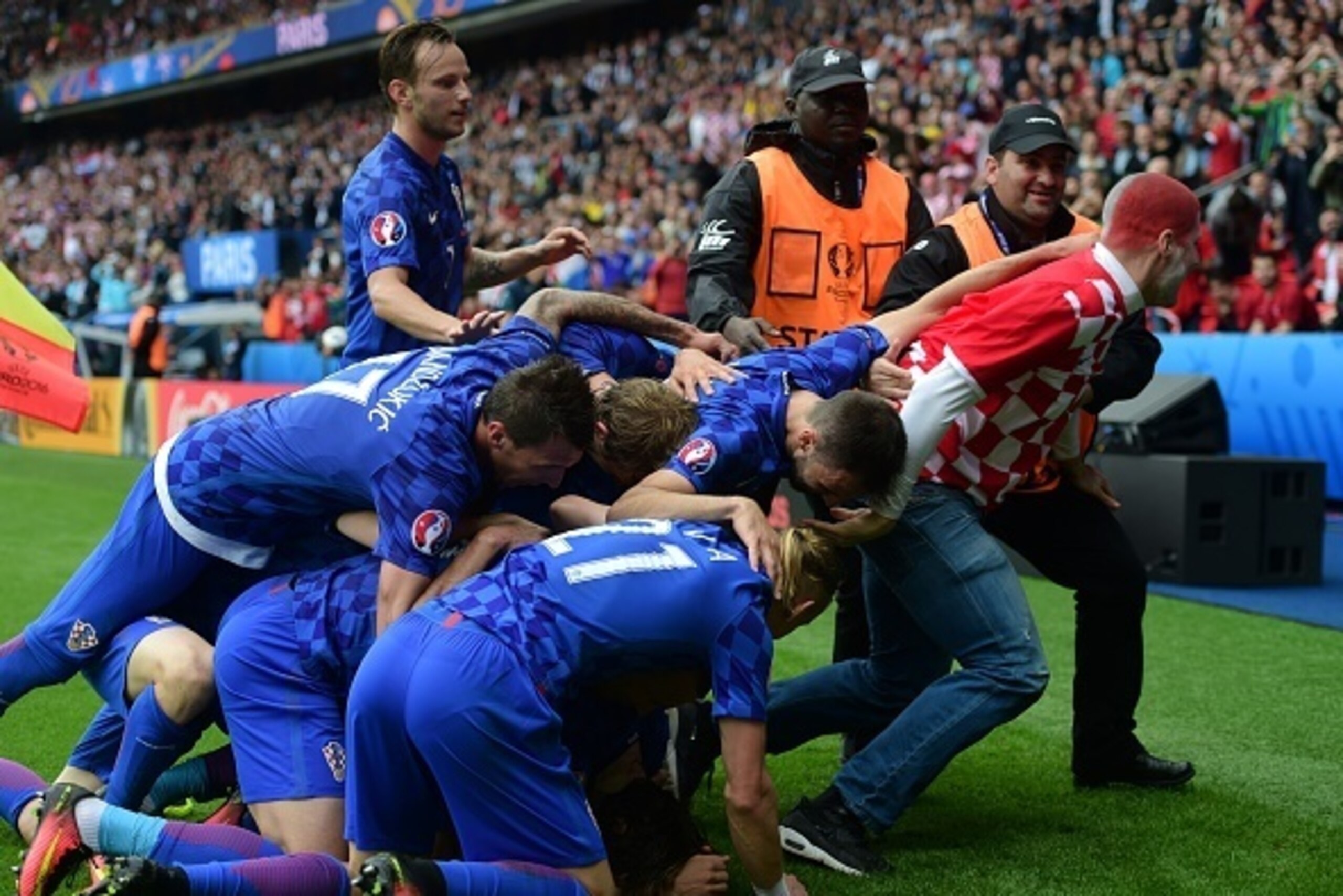 Security escort a fan off the pitch as he tried to celebrate with Croatia's midfielder Luka Modric who scored the team's first goal during the Euro 2016 group D football match between Turkey and Croatia at Parc des Princes in Paris on June 12, 2016. / AFP