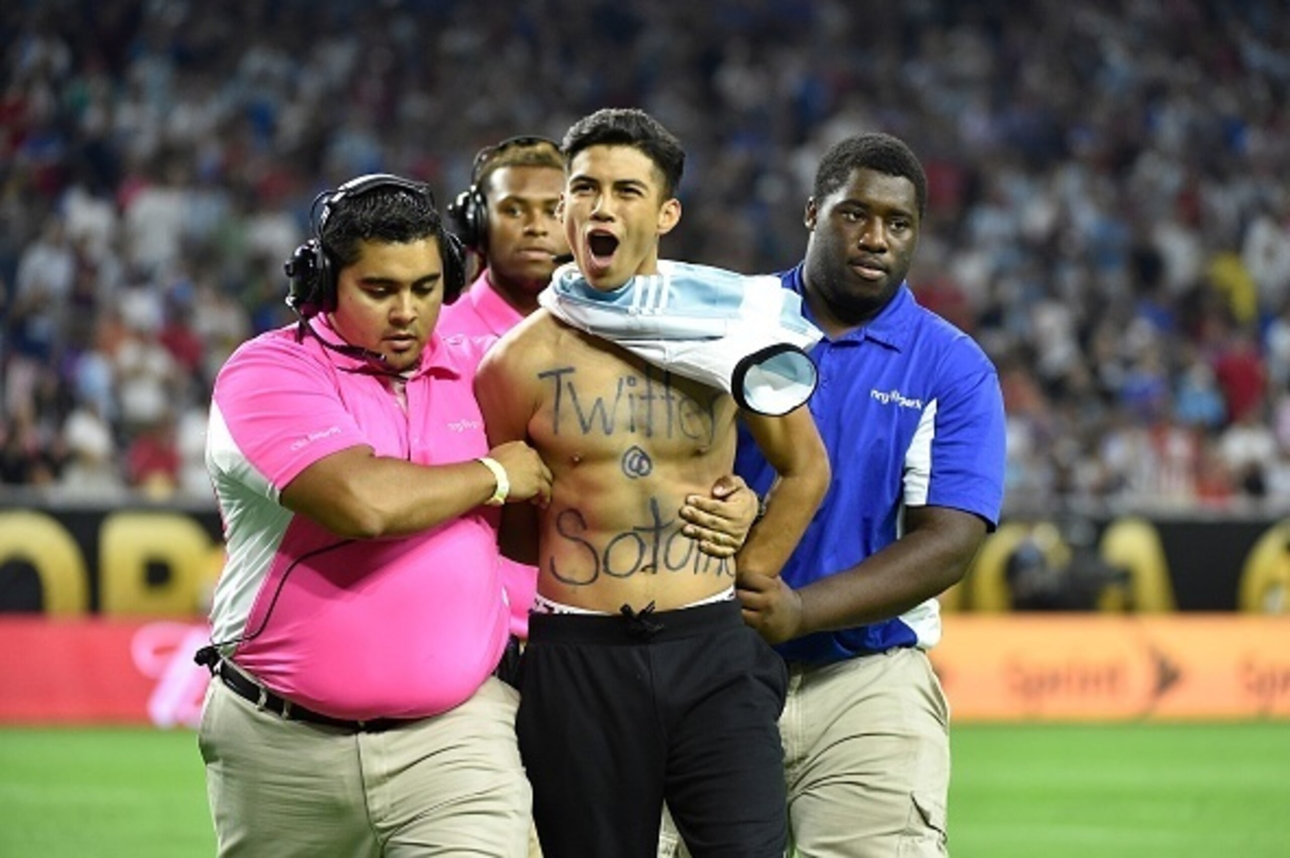 A fan of Argentina's Lionel Messi is taken out of the field after greeting him before the start of the second half of the Copa America Centenario semifinal football match against USA in Houston, Texas, United States, on June 21, 2016.  / AFP / Omar Torres