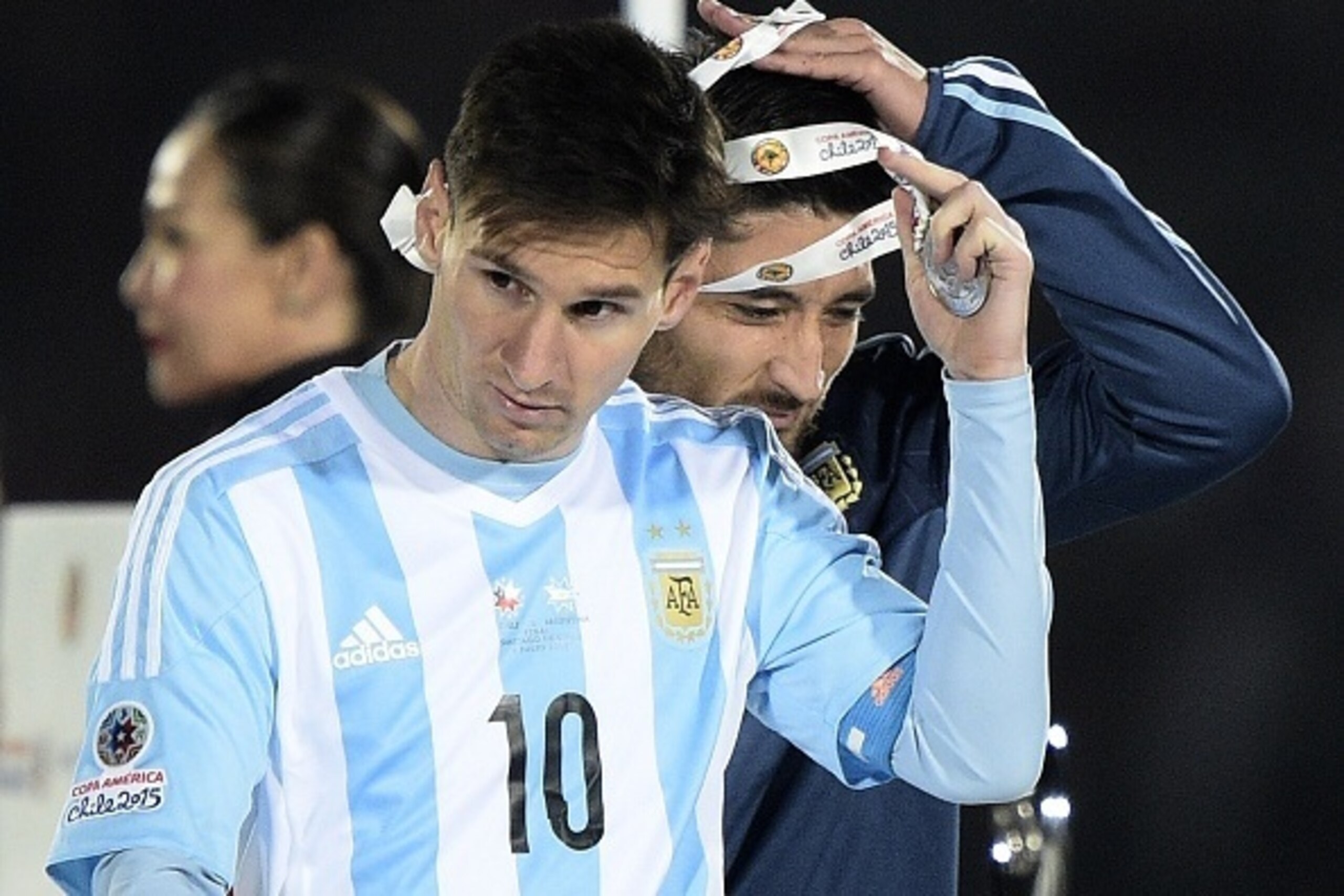 Argentina's forward Lionel Messi (L) and defender Milton Casco take off the second place medal of the 2015 Copa America football championship, in Santiago, Chile, on July 4, 2015. Chile defeated Argentina 4-1 in the penalty shootout. AFP PHOTO / JUAN MABR